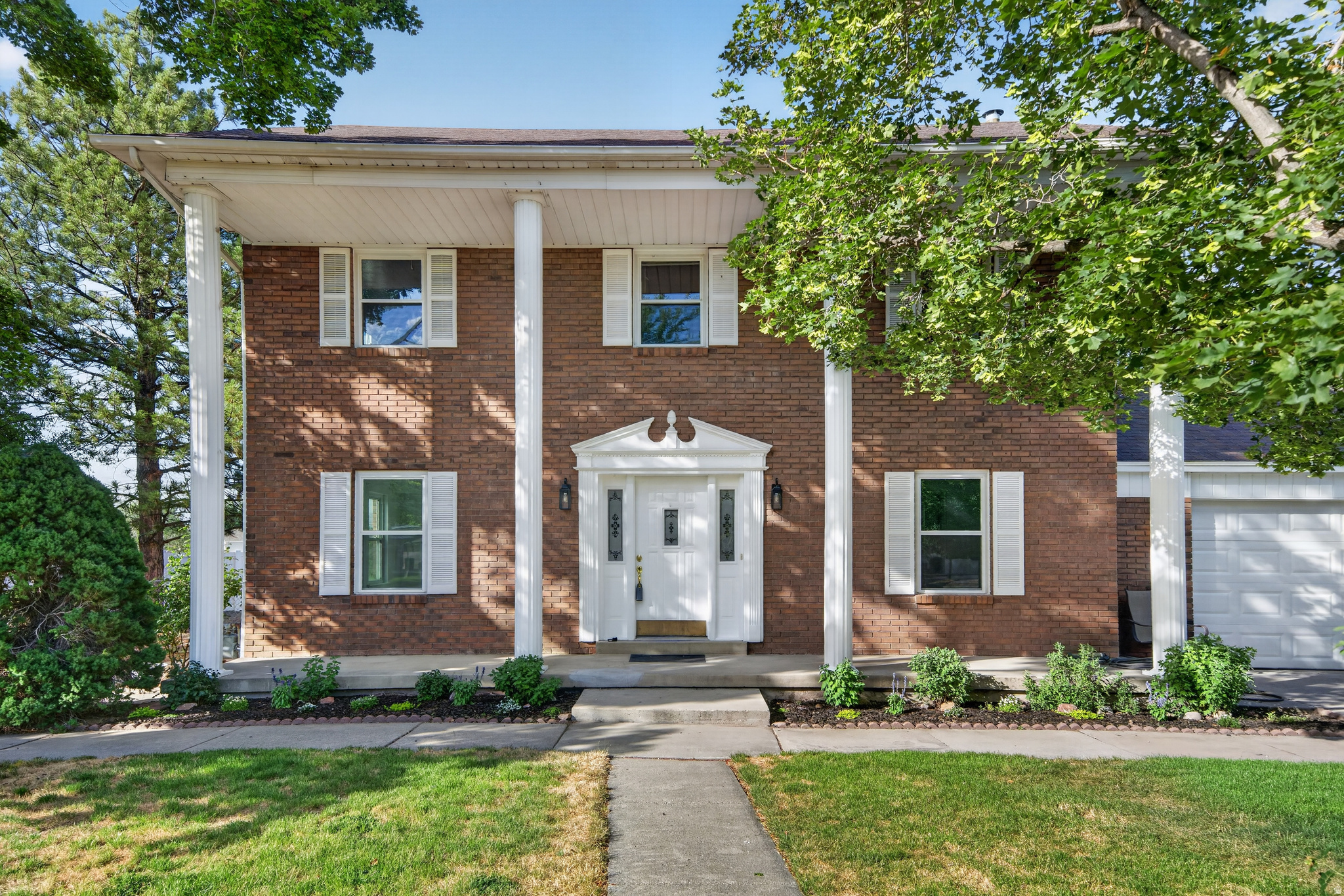 Located on a quiet cul-de-sac a block away from the Jordan River Parkway, you'll find this classic two-story beauty with timeless curb appeal! Framed by stately white colonial columns and charming red brick, this home makes a memorable first impression.  Inside, you'll find fresh paint, brand-new carpet, and updated electrical, making it move-in ready from day one. The spacious white-on-white kitchen opens to a cozy family room that features a wood-burning fireplace. Enjoy the flexibility of both a formal living room and a formal dining room that could easily serve as a home office. The showstopper is the enormous primary suite, complete with one of the largest en-suite bathrooms and walk-in closets you'll find-your own private retreat with room to spare! Need storage? This home delivers with a big butler style pantry, huge cold storage area, a large backyard shed, and a brand-new garage. Outside, there's plenty of room for all your toys with RV parking, plus a basketball hoop for hours of fun. The backyard has already been graded and is a blank canvas, ready for its new owners to create the outdoor oasis they've always imagined. Clean, spacious, and ready for immediate occupancy-this is a home you'll want to see in person!