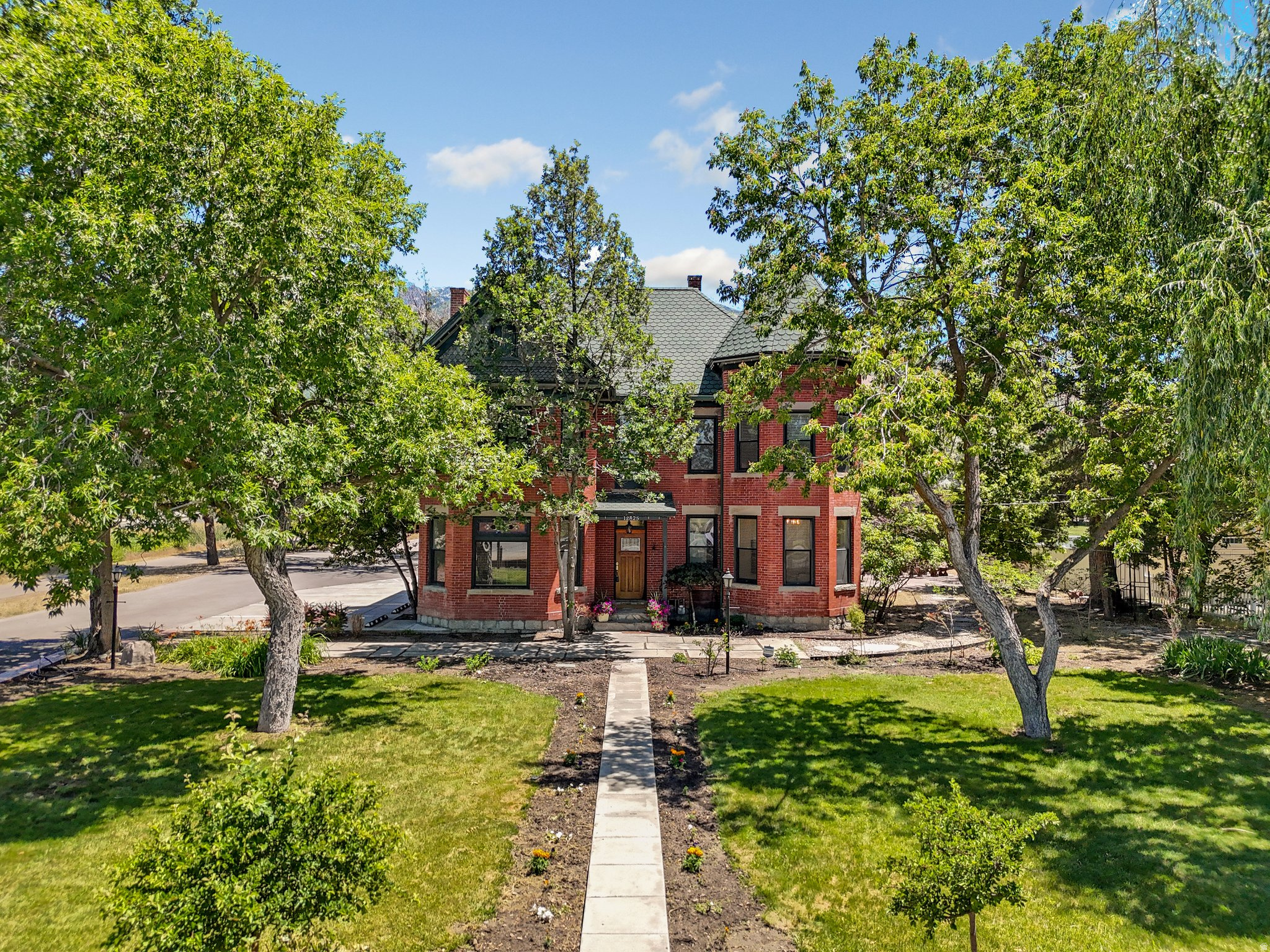 How do you even describe a home as special as this one? The Joseph S. Neilsen Home on Fort Street is a two-and-a-half story red brick Queen Ann with a granite foundation that sits on nearly an acre in Draper, Utah. But the legacy goes so much deeper. Built for Joseph, a school teacher and farmer, and his wife May, a musician; this home has been a happy place for families and friends for over a century. Over the years it has evolved from a family homestead with an orchard and vegetable garden, to divided apartments, to a full and glorious restoration to a historic mansion, and then its most recent transformation to Chestnut Pines where it was the only cafe in the United States to serve dishes exclusively from sprouted ancient grains. That brings our story to present day where this singular landmark property is ready for its next chapter where you become the next steward of our story.     There's no obligation to follow a script; if the past has taught us anything it's that this timeless home can adapt through the ages. The bones are original. That granite foundation is solid and holds 2.5 stories of red brick, a grand staircase, tall ceilings and original wood floors. Exposed brick is spotted throughout, accented by period-style doors and hardware along with bay windows that flood the front rooms with natural light. The craftsmanship connects with you a time when we built things to last, and makes you appreciate the past. Extra care has been given to keep the original character while also fully updating all electrical, plumbing, and HVAC and bringing the home into ADA compliance.     The kitchen is built for people who take food seriously; this was a farm and homestead, after all. That heritage is honored with modern updates like a butler's pantry with additional counter space, a beverage kegerator, two sinks, a mini freezer and fridge, and room to really make use of the fresh whole foods you could grow here. Behind the main home there is a renovated cottage that houses a fully equipped commercial kitchen. Whether you continue a food-focused operation, lease it out, or keep it for your own hobby kitchen, it's ready now.     You can still feel Joseph and May's vision come to life in the landscape. They raised their family here, and there is an honesty to the yard that hearkens back to a simpler time. Stamped concrete makes up the patio under a large curved iron trellis. A rock pathway leads to the botanical garden, custom gazebo with idyllic hanging swings, a rock waterfall, raised garden beds, and a fire pit. Beneath the beauty there's a new drip irrigation system that ensures every plant on the property is efficiently watered to thrive, blossom, flower, and fruit.     What you do with the property is only limited by your imagination. This home has a conditional use permit that is transferable to the new owner and has no expiration. Previous uses have included a cafe, outdoor gatherings/receptions, yoga, workshops, and wellness instruction. As you author your story it could include a salon, intimate venues, antique shop, medical, or artisan food production, to name just a few. It is zoned for both residential and commercial activity; it reverts just as naturally to a sensational and one-of-a-kind private residential estate if you're looking for a magazine feature-worthy mansion. It is not currently on the historic registry (though it could be) so you're free to remodel as you see fit. Four additional storage buildings, a six-car carport, and a large open corner lot with room to build a shop or guest house round out the property.     How will you help shape the heritage of this home? Come tour this near one-acre property. Feel the connection to the past. Soak up the history, then start writing your own chapter. The next story-your story-starts now.