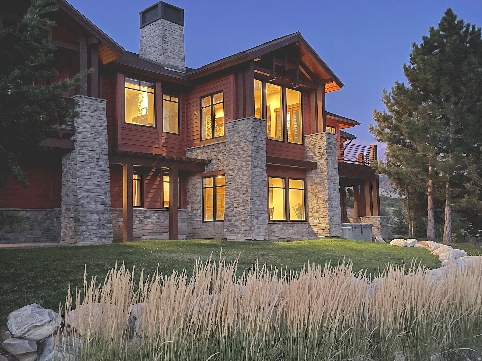 Designed by Bertoldi Architects and built by Big Canyon Builders, this fully furnished, turn-key mountain-modern retreat is perched atop the Highlands development in the heart of a ski mecca, offering elevated views of Pineview Reservoir, Snowbasin peaks, and Nordic Valley ski area. Open space to the front and side enhances privacy, while horses graze in warmer months and deer wander in winter, creating a serene alpine lifestyle.  The main level blends elegance and function with travertine tile and Brazilian hardwood floors. A gourmet kitchen features marble countertops, Wolf six-burner range, alder cabinetry, Sub-Zero appliances, dual dishwashers, and a raised island for entertaining. The living and dining areas offer coffered ceilings, stone fireplace, expansive windows, and deck access, all with panoramic mountain and reservoir views. The primary suite is a private sanctuary with fireplace, deck, spa-inspired bath, and walk-in closet, while a second main-level bedroom provides ensuite comfort.  The lower level is perfect for relaxation and entertaining, featuring a glassed-in wine room, stone fireplace, wet bar with Sub-Zero mini refrigerator, walk-out access to a Bullfrog hot tub, and a theater/media room. Three additional ensuite bedrooms with walk-in closets and granite finishes complete this luxurious mountain retreat in one of Utah's most coveted ski destinations.