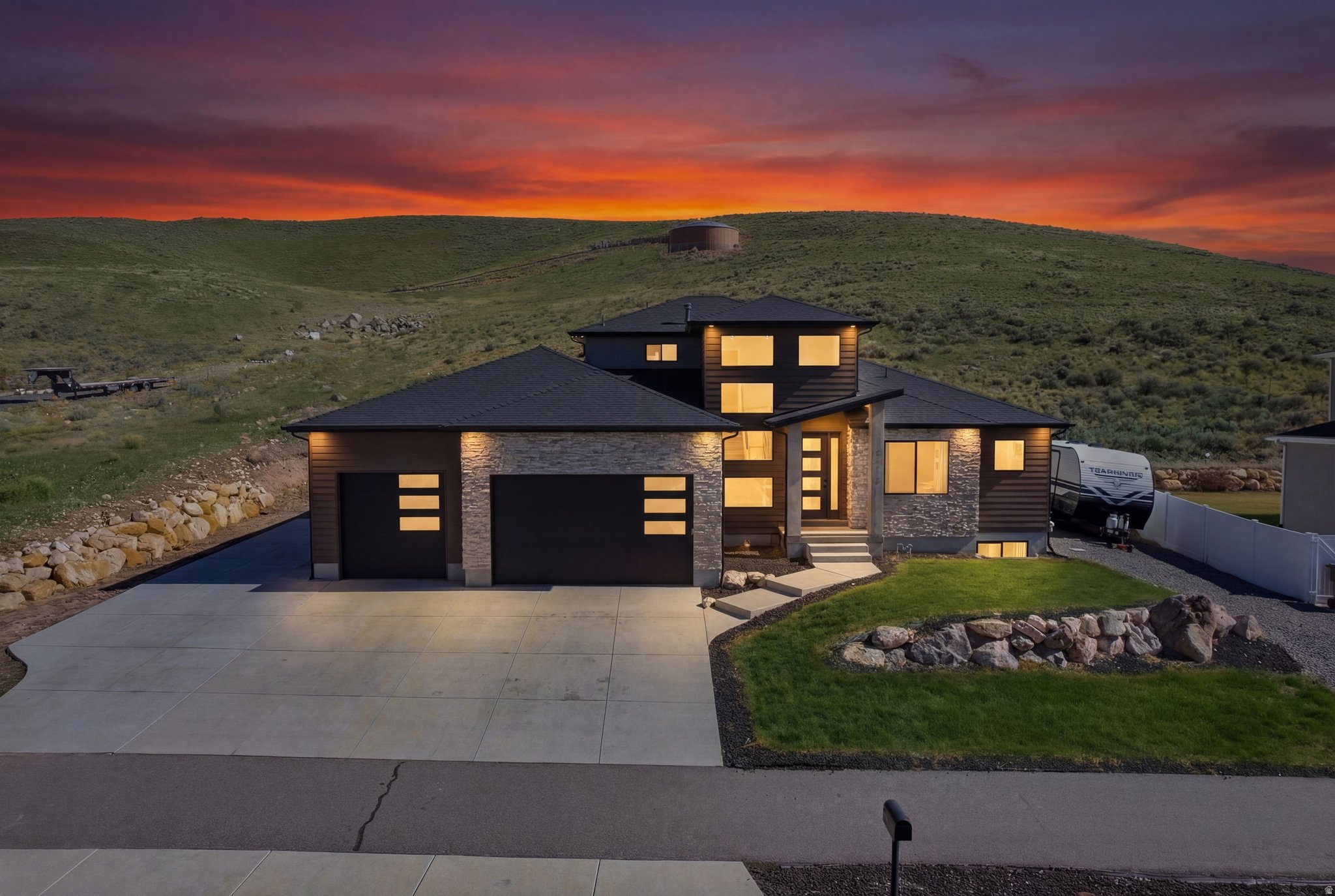 Experience mountain modern elegance in this hillside home by Argyle Homes, featuring breathtaking mountain and lake views and numerous high-end upgrades. Nestled against a hillside, the property offers ultimate privacy with no backyard neighbors. The yard is fully irrigated and thoughtfully designed with a second flat level, perfect for adding a pool, expanding the yard, or creating space for horses or other livestock. The private backyard features a large extended concrete patio with a built-in granite BBQ, creating the perfect space for outdoor entertaining, dining, and gatherings with family and friends.   This property offers exceptional parking  with space for large RVs and additional vehicles. One side features a 35-foot gravel space with full RV hookup, while the other side has a 40-foot cement pad, providing ample parking for all your toys and guests.   Inside, oversized windows fill the home with natural light and showcase the stunning views of the mountains and lake.   The kitchen is a chef's dream, boasting a massive island, abundant soft-close cabinetry, and ample storage. A large walk-in pantry provides even more space for kitchen essentials, while the generous dining area easily accommodates a very large table-perfect for family meals or entertaining guests.  The main-floor primary suite includes a soaking tub, dual sinks, and a separate shower, with laundry conveniently located on both the main level and basement.  The basement features soaring 9-foot ceilings and luxury vinyl plank flooring throughout. It offers a spacious entertaining area, a stylish bathroom with an adjoining laundry space, ample storage, and a mechanical room with a water softener-combining practicality with comfortable, versatile living.   With stunning views, generous yard space, full irrigation, and exceptional parking, this home offers a rare combination of modern elegance, functionality, and privacy.  Included appliances: two washers, two dryers, and the refrigerator, providing convenience and move-in ready functionality.  All information should be independently verified by the Buyer. The current owner has had the home professionally tested and cleared for both meth and radon; copies of the reports are attached for review.