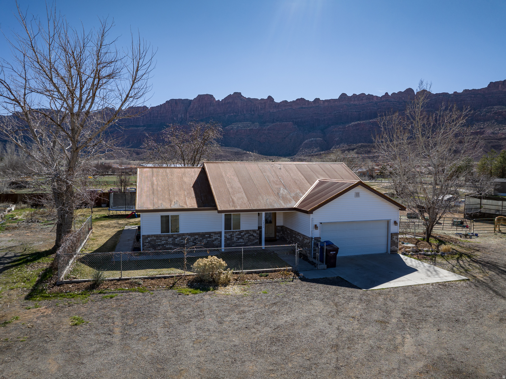 Modern Ranch Living with Breathtaking Moab Vistas Experience the perfect blend of high-desert beauty and thoughtful interior design in this 3-bedroom, 2-bath ranch-style home located on a one acre lot. Flooded with natural light, the open-concept kitchen and living area serve as the heart of the home, designed specifically for easy gatherings and a seamless flow. The primary bedroom is a true sanctuary, boasting a spacious en suite bathroom with a deep soaking tub and dual walk-in closets. Just off the kitchen, a bright flexible space that opens to the back patio is currently utilized as a playroom, but offers the versatility to become a home office, reading nook, or yoga studio. Throughout the home, large windows perfectly frame panoramic views of the Moab Rim and the La Sal Mountains. The exterior is fully prepared for equestrian life with secure fencing to keep your horses safe. Water rights easily support the mature trees and garden area. A large barn equipped with high-voltage power provides an ideal setup for a workshop or heavy equipment. Additionally, the property features a detached outdoor shed that has been creatively converted into a quiet, comfortable office space, offering a private retreat for remote work away from the main residence.