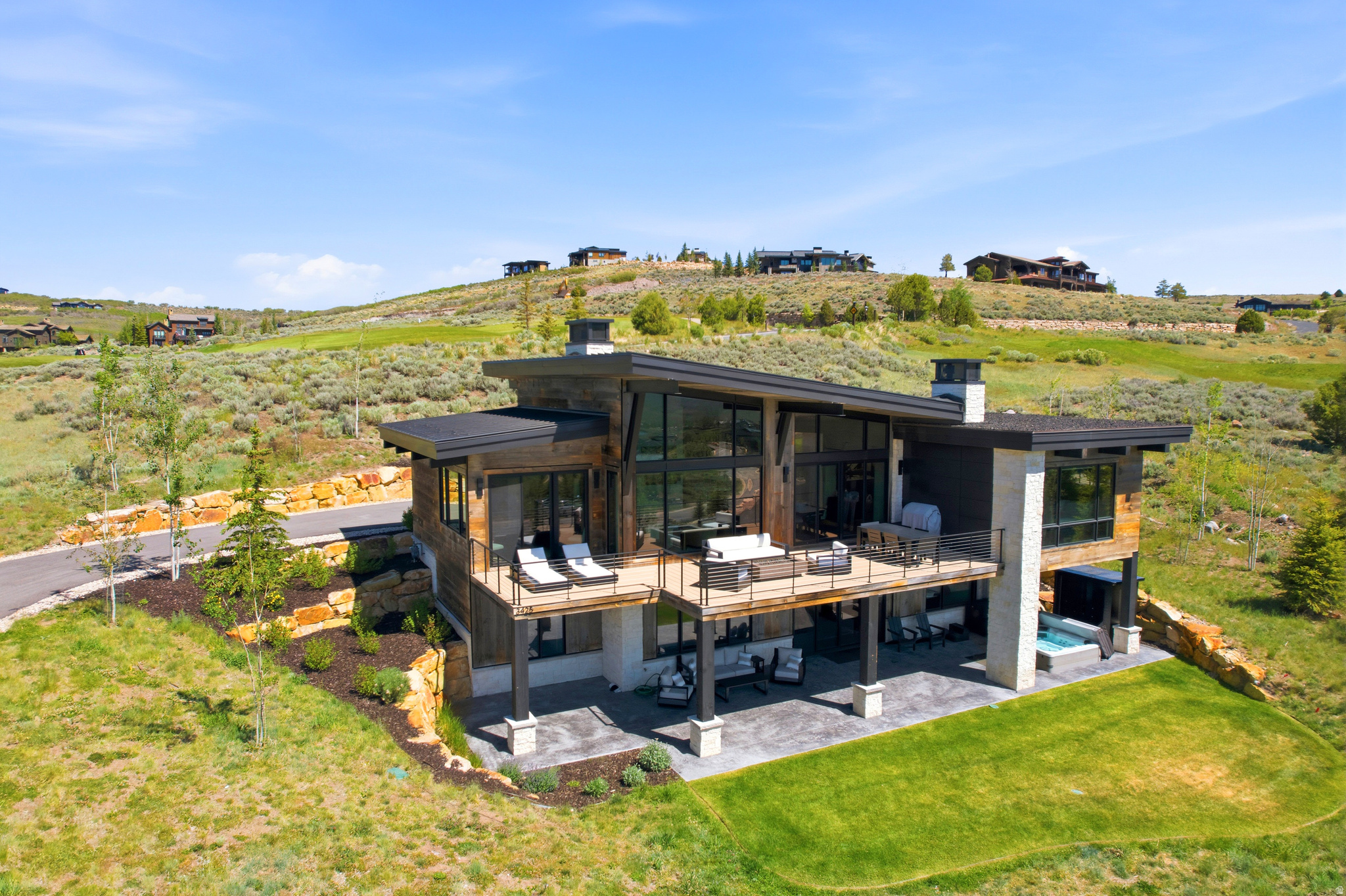 Situated within the gated community of Tuhaye, this custom residence is perched on 0.83 acre on a quiet cul-de-sac with sweeping mountain and valley views. This custom residence offers thoughtfully designed living space and blends sophisticated mountain architecture with quality craftsmanship and timeless materials.  Designed for both comfortable daily living and effortless entertaining, the main level is anchored by a dramatic great room with floor-to-ceiling windows, wide-plank hardwood flooring, and an open-concept layout in the kitchen, dining, and living areas. The well-appointed kitchen features Thermador appliances including a six-burner gas range with griddle and double ovens. The expansive south-facing deck extends the living space outdoors and captures the panoramic views. Both a primary and guest suite on the main level provide convenience and flexibility. The walkout lower level offers 2 additional bedrooms, bunk room, 3 baths, a living area and game room, and a patio with a hot tub.  Throughout the home, Austin limestone, reclaimed barn wood, and designer Hubbardton Forge lighting reflect the commitment to quality and attention to detail. The two-car garage with built-in cabinetry and an epoxy floor provides ample storage and functionality.  Offering a rare combination of privacy, craftsmanship, and expansive views, this residence represents an exceptional opportunity to experience mountain living within one of the Park City area's premier private communities.  A Full Talisker Club Membership is included, providing access to a multitude of private amenities such as: clubhouses, Kid's Club, spa, fitness center, pools, tennis and pickleball courts, and the Mark O'Meara-designed golf course, along with a 9-hole par-three course. Membership also includes Talisker's Empire Pass amenities- ski-in/ski-out lounge at Deer Valley's Silver Strike Express lift, a private lodge, pool, fitness center, and spa- creating an unmatched year-round lifestyle experience.