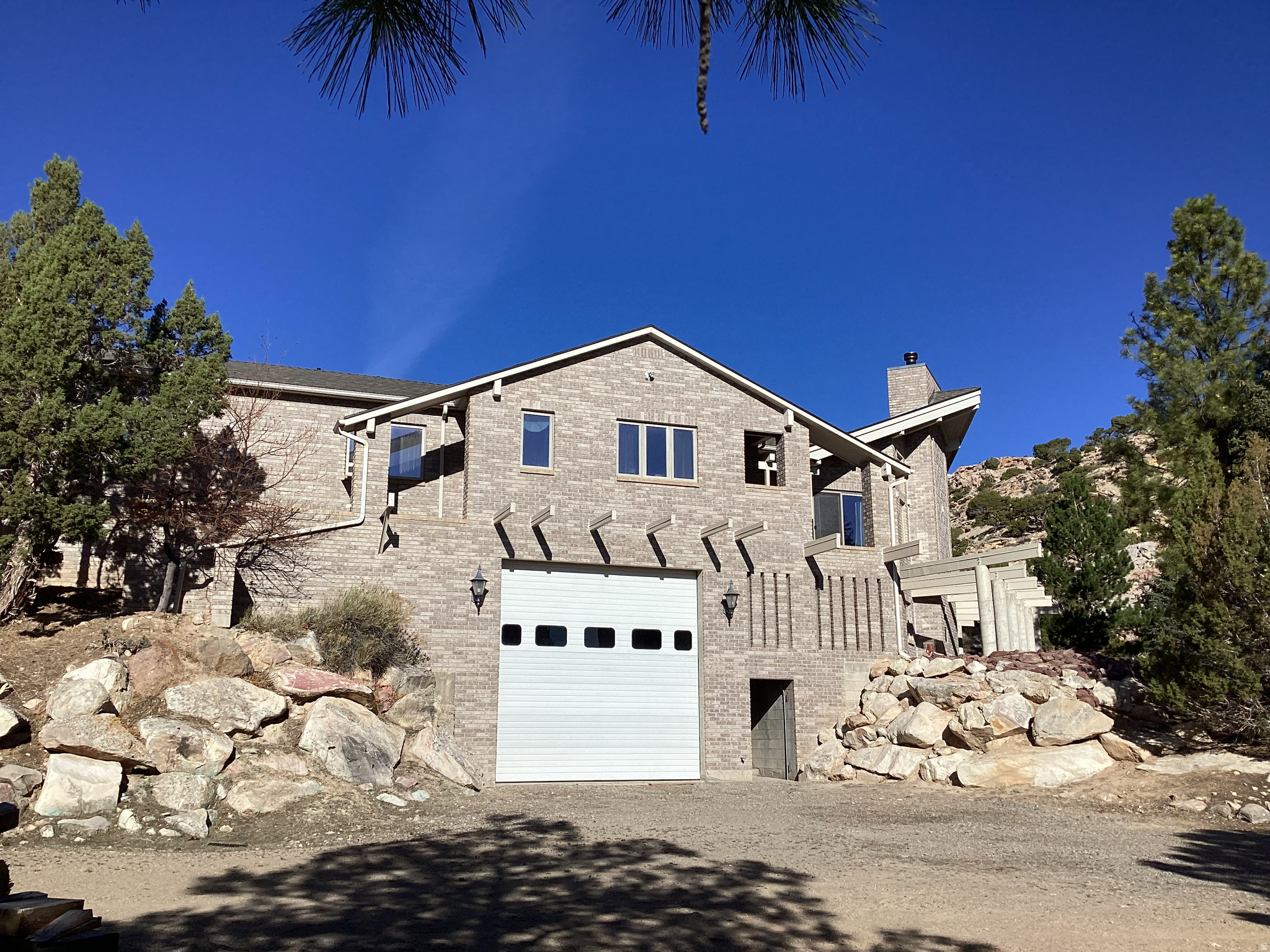 This stunning house needs YOUR FINISHES!  It's approx 80% done.  The block/masonry work is beautiful.  4 bedrooms and 4 baths on 1 acre. VIEWS!  Mature trees and stunning low maintenance natural earthwork.  CIRCULAR driveway to ground floor entrance in back.  Give this home your classy taste and make it your own!   RV GARAGE DOOR IS 14'H.  On WYO side of Manila.