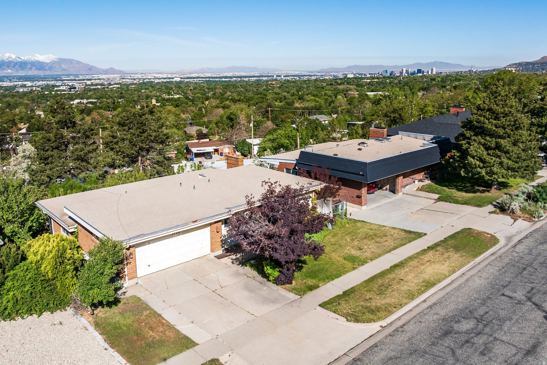 Perfectly positioned in Salt Lake City's coveted east bench neighborhood, this spacious mid-century residence presents an exceptional opportunity to create something truly special. Full of character and incredible potential, the home offers timeless architectural elements, generous living spaces, mature landscaping, and sweeping valley views. The main level features an expansive living room framed by large windows and direct access to a deck that spans the entire backside of the home, creating a seamless connection to the outdoors and capturing beautiful city and mountain views. A formal dining room adds a fun and distinctive architectural element, while the layout provides outstanding functionality with two secondary bedrooms, a full bath, and a primary suite with its own three-quarter bath. The lower level offers remarkable flexibility with an additional bedroom, three-quarter bath, full second kitchen, and generous entertaining spaces. A large family room centers around a striking stone fireplace and unique dry bar, while an adjacent den provides ideal space for a home office, game area, fitness space, or additional lounge. Walkout access leads to a covered patio, mature grounds, garden area, and a private basketball court surrounded by mature trees. Located just minutes from the University of Utah, downtown Salt Lake City, world-class outdoor recreation, and nearby canyon access, this is an incredible opportunity to reimagine a home with great bones in one of the city's most desirable neighborhoods.