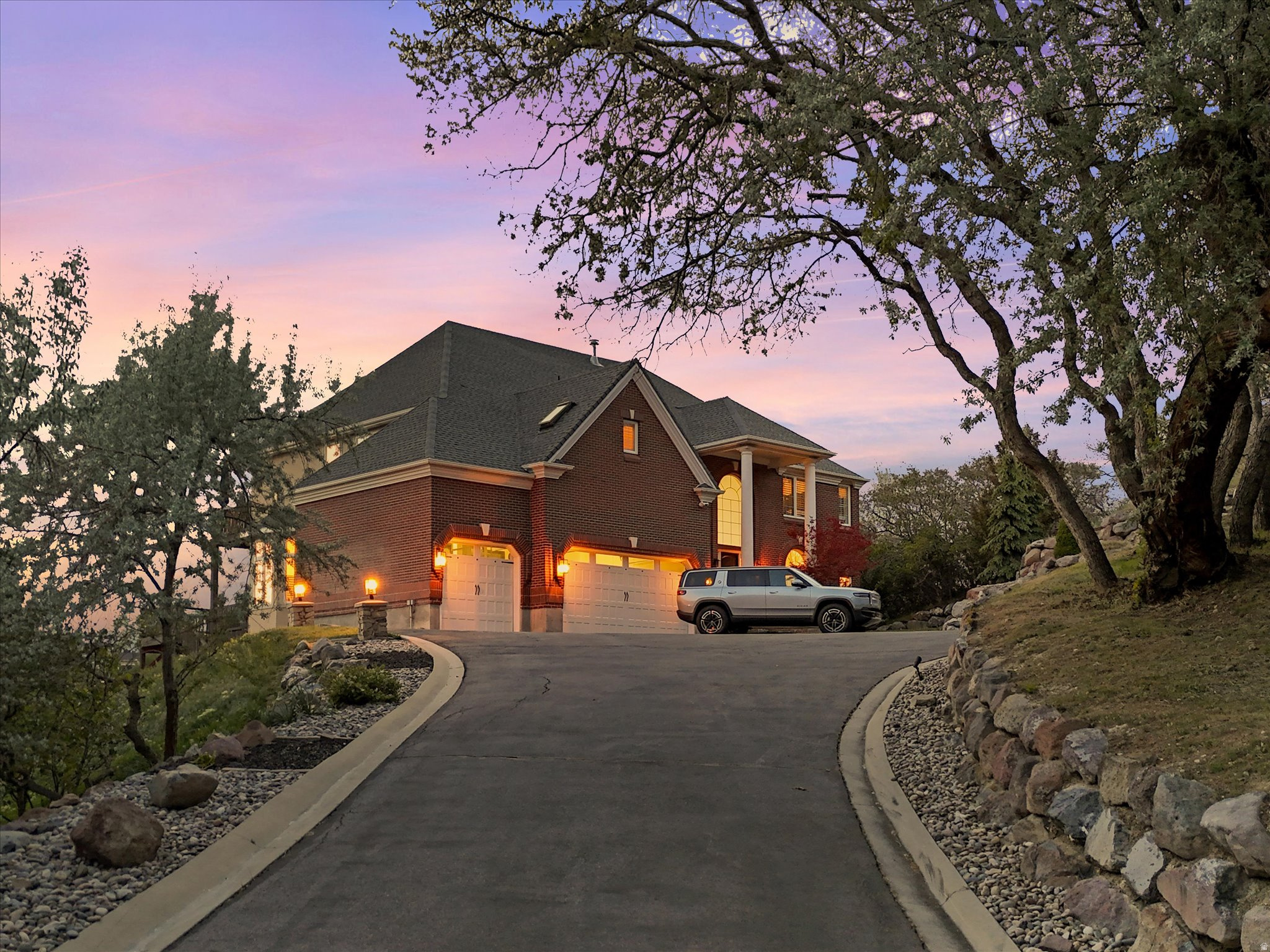 Settle in and enjoy the views. Thoughtful updates throughout breathe new life into this two story traditional on nearly two wooded acres. Atop a long sloping drive, the house sits just above the tree line providing unobstructed views of both the Wasatch Front and the Salt Lake Valley below.   The homes light filled interior strikes just the right balance between classic elegance and modern comfort - from formal entertaining spaces to spacious bedroom suites awash in neutral tones with an emphasis on natural materials.  A sweeping grand staircase greets guests as they enter the foyer and pass through the homes public spaces. Just beyond the grand staircase, a short hall opens up to the great room and eat-in kitchen. Through one set of French doors you'll find a private den and through another an expansive outdoor deck.  Back inside, the homes large updated kitchen takes center stage with two islands featuring waterfall countertops, an expansive breakfast bar, separate dining nook with bay window, and a walk in pantry. A fully renovated main floor laundry room features floor to ceiling cabinetry and classic checkerboard floors. American White Oak floors soaked in natural light from walls of windows are featured throughout the main floor, second floor hallway, and primary suite.  On the homes second level are four en suite bedrooms including a show stopping primary suite with separate sitting area. Built-ins frame a fireplace on one wall while French doors lead onto a private deck with views of the mountains and the valley below. A fully renovated spa-like bathroom begs you to relax and again take in the view through a nearly floor to ceiling picture window located in the oversized two person walk-in shower. Dual walk-in closets, one with en suite laundry round out the generous amenities in the primary suite. Three additional en suite bedrooms each with their own fully renovated bathrooms featuring new fixtures and glass wall tiles in individual colors.  Two additional bedrooms and one additional bathroom are located on the homes lower level along with a second kitchen and living area. In addition to this mother-in-law suite, extensive storage and a large covered patio can also be found on the lower level. An uncovered portion of the patio has been configured for a hot tub. The walk out basement provides direct access to the backyard with its wood burning fire pit encircled by the thicket of native scrub oak that frames the property.