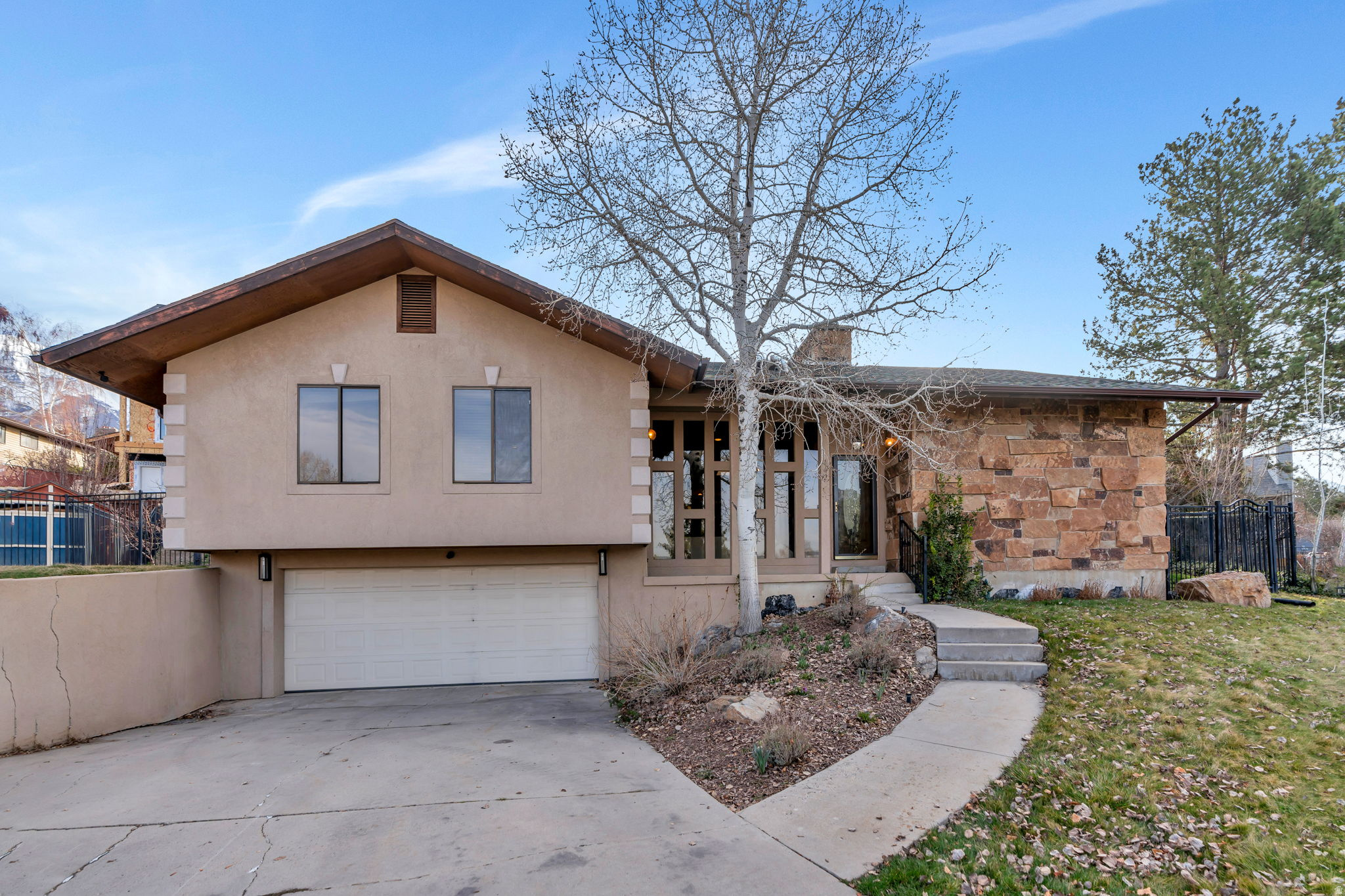 Beautiful midcentury modern rambler tucked away on a quiet cul-de-sac, originally featured in the 1978 Parade of Homes. This distinctive property showcases timeless architecture with a striking stone and stucco exterior and large picture windows that fill the home with natural light. Upgrades also include a roof replacement installed the first week of March 2026. Step inside to soaring vaulted ceilings, skylights, and a spacious formal living room with a stunning stone fireplace. The kitchen features white cabinetry, a gas range, and abundant storage, with a natural flow into the dining area and an additional living space. The oversized primary suite offers generous natural light and a beautifully updated ensuite bathroom with dual sinks, a soaking tub, walk-in shower, and a large textured window for added privacy. The walkout basement includes a large living area with another fireplace, a storage room, and a bedroom or office space. Outside, enjoy a fully landscaped and fenced backyard with mature trees and a covered patio, perfect for relaxing or entertaining. Conveniently located near parks, hiking trails, the Murdock Canal Trail, and just minutes from State Street for easy access to shopping and dining. Measurements provided as a courtesy only, buyer to verify all info.