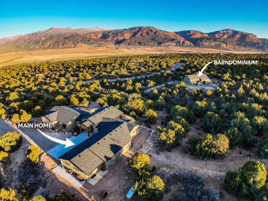 Private hilltop retreat away from the crowds. 10 miles west of Cedar and situated on 20 secluded acres, this stunning property offers panoramic views into Kolob Canyon & surrounding landscapes and is near Kanarraville and New Harmony. This beautifully designed home features 4 bedrooms/ 5 bathrooms, showcasing custom, high-end appliances & exceptional finish work throughout. Designed w/ both luxury & functionality in mind, the property includes a detached barndominium complete w/3 indoor horse stalls & an outdoor round pen, making it ideal for equestrian enthusiasts. Enough garage space w/the ability to accommodate up to 7 vehicles, including an oversized 16-ft pull through garage door. Residents can enjoy access to the community's HOA equestrian center w/many additional amenities. Experience privacy, luxury, and scenery all in one extraordinary property.