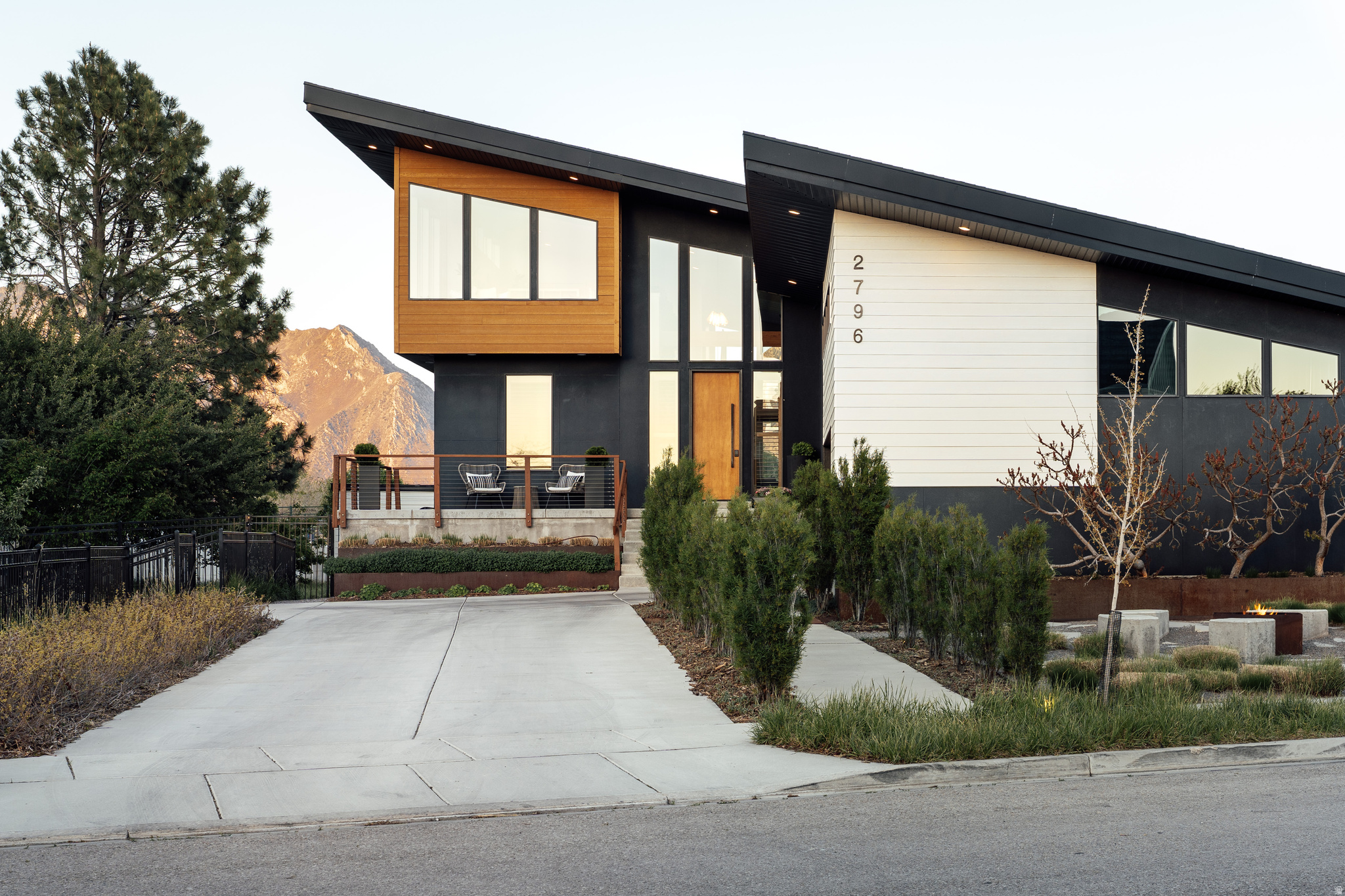 Out where the air feels a touch quieter and the skies stretch just a bit wider - this modern architect-designed gem lies tucked between vistas of Lone Peak and Timp - where thoughtful design meets wide open play just minutes from Silicon Slopes, Thanksgiving Point and American Fork Canyon. Set on just over half an acre, the property unfolds like a private playground. A winding path loops the backyard among wild grasses and strawberries - perfect for bike rides that turn into sunset laps - while double trampolines, the splash of a modern creek, and a tiered deck invite daily adventure. You'll truly feel the seasons change through soaring windows with uninterrupted views of rural farmland and mountain peaks. A firepit out front sets the scene for slow evenings, while a chicken coop surrounded by fruit trees adds a charming, self-sufficient touch. You'll soak in the 15-foot swim spa under twinkling tea lights and sweat in the traditional cedar sauna. Inside, the home leans elevated and entirely livable. Vaulted ceilings anchor the main living and kitchen spaces, bringing in light and volume, while a generously-sized pantry keeps everything tucked neatly out of sight. For those with a sense of play, a rock-climbing wall leads to a tucked-away secret room complete with overhead netting that transforms the upper level into an imaginative retreat with mini-theater room. The expansive upstairs bonus area captures some of the home's best views, while a walkout basement offers a second family room with easy access to the outdoors. With 7 bedrooms and 3.5 baths, there's room here to spread out and settle in. An extra-wide two-car garage (complete with an electric vehicle charger and over 40-feet of built in storage), solar panels, and water-conscious landscaping speak to efficiency. This is a home built not just for living, but for living well, with just the right amount of adventure and luxury woven in.