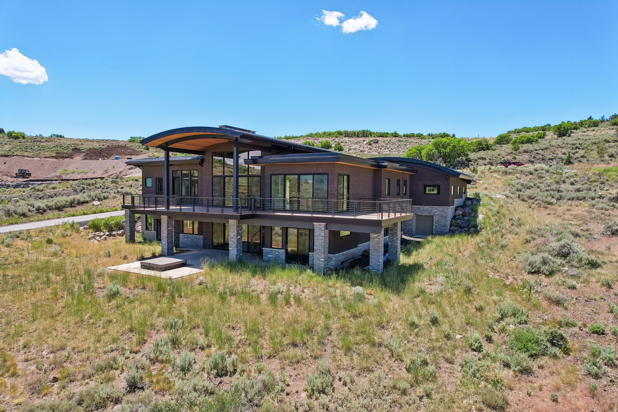Set in Tuhaye outside Park City, 9009 N Uinta Drive makes an immediate impression with a stunning great room, vaulted ceilings, and a wall of glass that looks past the deck to wide, sweeping views of the Uinta Mountain Range and Hoyt Peak.   Built in 2020, this 5,976 sq ft residence offers 4 bedrooms, 6 baths, European-style countertops and finishes, and a great room fireplace with metal and rock detailing that reads like a work of art. The main-floor primary suite opens to a separate flex lounge, ideal for media, office, studio, or quiet retreat use. The kitchen includes a butler's pantry, while the lower level adds three ensuite bedrooms, a family room with fireplace, and a theater setup for elevated everyday living.   Outdoor spaces include an upper deck, lower patio, spiral staircase connection, built-in hot tub, and 1,650 sq ft of covered deck. Systems include radiant heat, upstairs mini-split AC, a solar array, Tesla Powerwalls, and a German whole-house ventilation and pressurization system with individual room extraction and included carbon filter capability. The 1,150 sq ft garage features a suspended floor, stairs to a lower workshop, and exterior workshop access.   Talisker Club membership is offered separately and is not included; membership is available for $200,000 and may provide access to golf, swimming, dining, and on-mountain ski amenities.