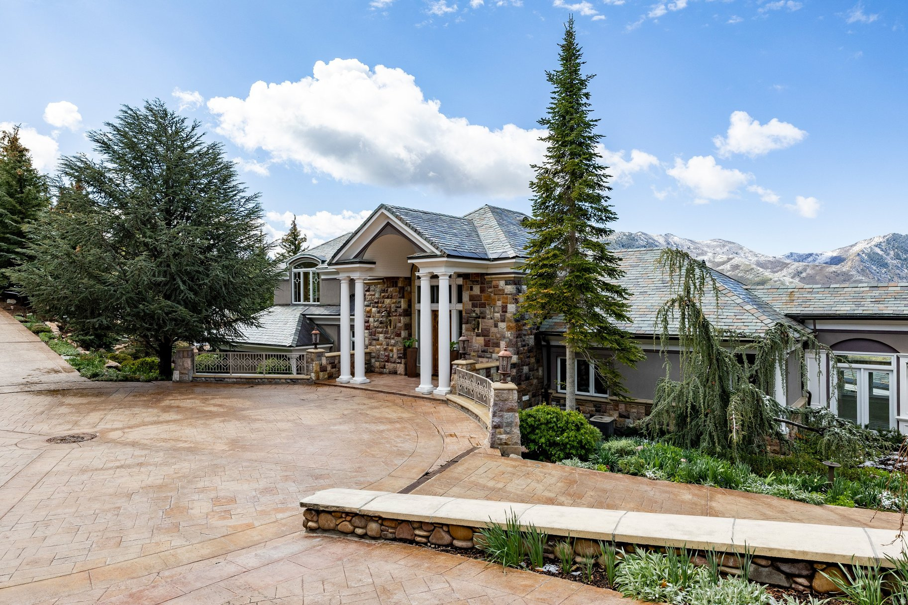 A true mountain sanctuary-7 acres of privacy, just minutes from the city. Tucked into Emigration Canyon and surrounded by towering pine, spruce, and fir, this estate offers a level of calm and seclusion that's increasingly hard to find-yet you're still moments from downtown. It's the kind of setting where mornings feel slower, evenings stretch longer, and the outside world fades just enough. Inside, the home balances scale with warmth. The kitchen-finished with granite countertops-is designed to gather around, whether it's a quiet morning coffee or a full house for the holidays. A dedicated fitness room creates space to reset without ever leaving home. The primary suite feels like its own retreat, with a steam shower that turns everyday routines into something restorative. Upstairs, hand-carved wood detailing and a statement fireplace add depth and character you simply don't see in newer construction. The layout offers flexibility without compromise. A private guest suite-with its own laundry and kitchenette-makes longer stays easy and comfortable. A separate apartment, complete with its own garage, opens the door for true multigenerational living, long-term guests, or added independence. And outside-this is where the property really separates itself. Multiple outdoor living spaces are intentionally positioned for privacy, surrounded by mature evergreens, creating a setting that feels both intimate and expansive at the same time.
