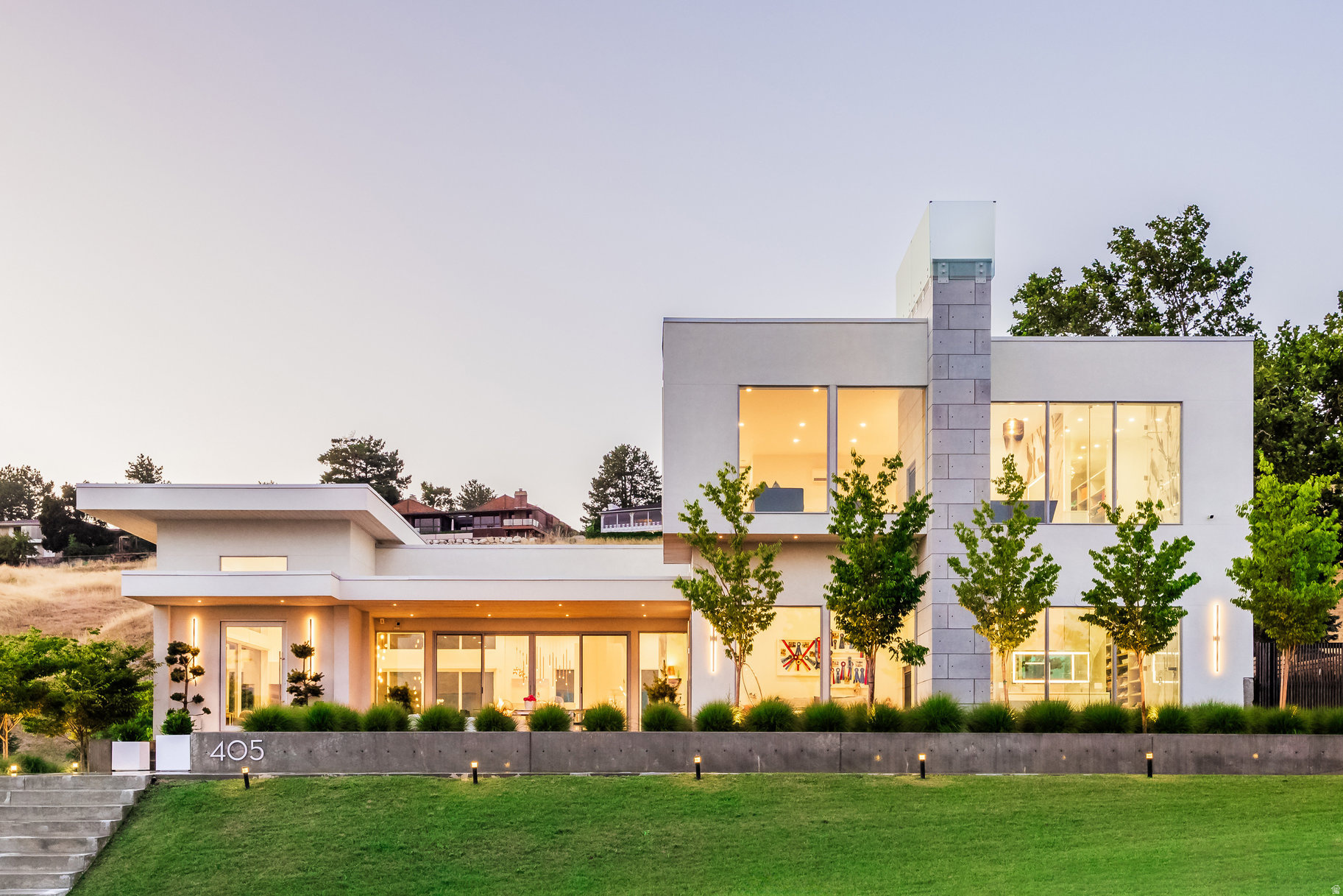 Exceptional contemporary residence perched in the Upper Avenues of Salt Lake City, commanding unobstructed views of the valley, city lights, and surrounding mountains. Built in 2020, this home showcases refined modern design and premium craftsmanship, featuring custom Poliform cabinetry throughout, 34/" white ash hardwood floors, Windsor commercial-grade windows and doors, a climate-controlled garage with generator, and heated bathroom floors. A striking formal entry with soaring 15-foot ceilings sets the tone, opening to an expansive main-level living space anchored by a dramatic fireplace and thoughtfully designed seating areas. The chef's kitchen is both elegant and functional with Miele appliances throughout, including a separate refrigerator and freezer, wine refrigerator, and dual dishwashers. A stunning 16-foot island and oversized working kitchen/butler's pantry make this home ideal for elevated entertaining. The dining area opens via sliding glass doors to a private patio with a fire pit, creating seamless indoor-outdoor living. The home offers two luxurious primary suites, providing exceptional versatility and breathtaking valley views. The main-level suite features a fireplace, his and hers closets, and a spa-inspired bath with a soaking tub and separate shower. The upper-level primary retreat serves as private sanctuary, complete with a sitting area and fireplace overlooking the city, dual closets and vanities, and a spacious shower with separate tub. The lower level offers 12-foot ceilings and is designed for relaxation and recreation, featuring a large family room/home theater, wet bar with Scotsman ice maker and refrigerator, bedroom, full bathroom, and a flexible room ideal for a home office or fitness studio. Additional unfinished space presents the opportunity to customize and expand the living area to suit your needs.