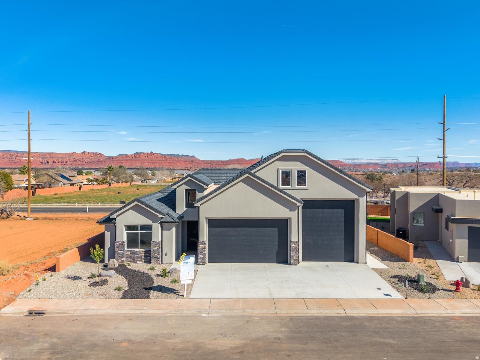 Welcome to Black Stone in beautiful Ivins, breathtaking Red Mountain backdrop. This brand-new home showcases stunning views, thoughtful design, and elevated finishes throughout. An inviting open floor plan is highlighted by luxury wood-plank flooring, both stylish and durable, perfectly suited for Southern Utah living. The kitchen is truly the heart of the home, featuring custom knotty alder cabinetry with rich natural wood grain, soft-close hardware, and detailed craftsmanship. Designer selected granite countertops pair seamlessly with a modern stacked tile backsplash and stainless-steel appliances, creating a warm space ideal for everyday living and entertaining. The spacious living room offers tall ceilings and is plumbed for a future fireplace, providing the perfect setting to gather and relax. A convenient half bath is located just off the main living area for guests. The main level includes two secondary bedrooms with a full bathroom, along with a beautifully appointed primary suite. The primary bath features sleek finishes and a spa-like atmosphere, complete with a 3/8" Euro glass shower enclosure. Upstairs, you'll find a versatile bonus room with its own full bathroom, ideal for a media room, office, gym, or private guest retreat. It is also plumbed for a mini-split system, allowing for customized climate control. Additional highlights include the entire home plumbed for central vacuum, a fully landscaped yard with room for a future pool, and exceptional garage space with a 12' wide x 14' tall RV garage door plus an oversized two-car garage with an 18' wide, 10' tall door. Offering space, quality craftsmanship, and unforgettable Red Mountain views, this home is a rare opportunity in one of Ivins' most desirable communities.