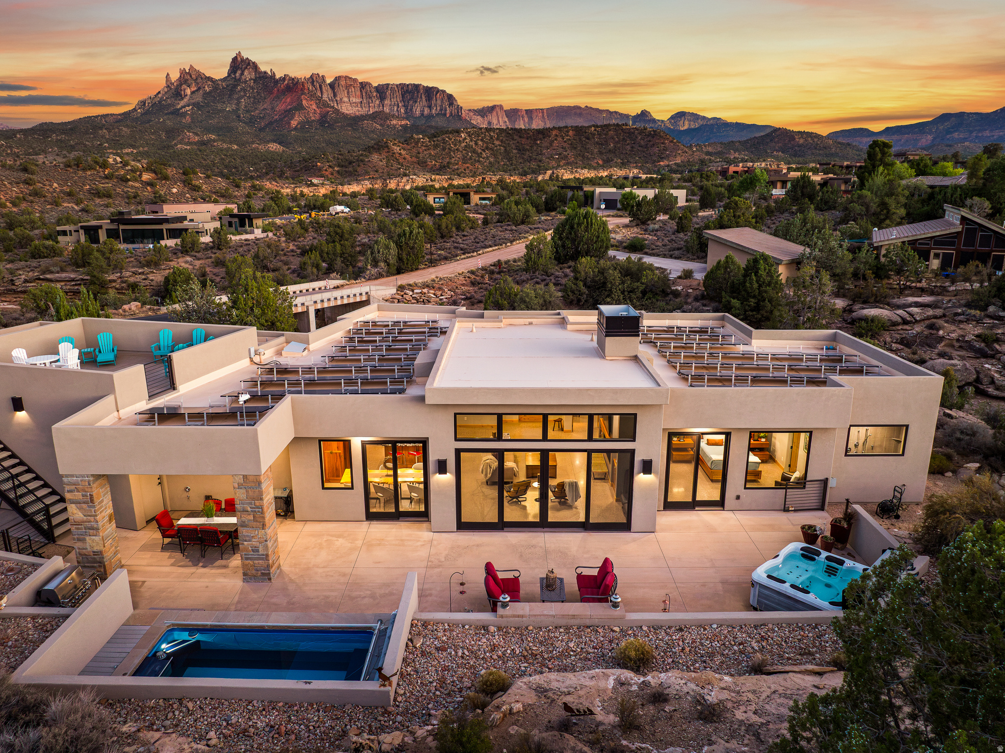 Incredible custom home built and designed by renowned Zion Canyon builder Mark Fahrenkamp, with intentional details specifically designed to enhance privacy and views. Anasazi Plateau is Springdale's premier community - set on over nearly 300 acres with only 77 homesites, meaning generous open space between homes. Set above the valley floor and away from tourist congestion, this spectacular oversized 0.77-acre lot leaves plenty of room to build an accessory dwelling. Built in 2017, the 4-bed, 3-bath home offers direct sightlines to West Temple, Mt. Kinesava, Eagle Crags, and the cliffs that define the gateway to Zion National Park. Inside, the Great Room opens to 13-foot vaulted ceilings, polished concrete floors, tall Alder doors, and cherrywood cabinetry - finishes chosen for durability as much as design. A gas fireplace warms the space through the cooler shoulder seasons. The kitchen is built for the way people entertain: Wolf appliances, Sub-Zero refrigeration, and leathered granite countertops that hold up to real use. The primary suite faces Mt. Kinesava directly, with a steam shower, dual heads, and a custom walk-in closet system. A second ensuite keeps guests comfortable, while the remaining bedroom and a dedicated office overlook the cliffs and natural wash below. Outdoor living is where this lot earns its premium. The 1,176 sq ft patio is shaded and oriented for long Springdale evenings, anchored by a firepit, a Bullfrog hot tub, and an Endless Pools Swim Spa. The rooftop deck delivers a full 360 vantage - sunsets across the canyon, storm fronts moving along the cliffs, and canyon wildlife passing through at the natural pace of the high desert. On the practical side: 50 solar panels keep utility costs low, the 1,144 sq ft three-car attached garage handles the gear that comes with living this close to the park, and all major appliances convey. Trailheads, the Zion shuttle stop, and Springdale's restaurant corridor are minutes from the door. Homes in Anasazi Plateau don't come around often. This one shows what's possible when they do.