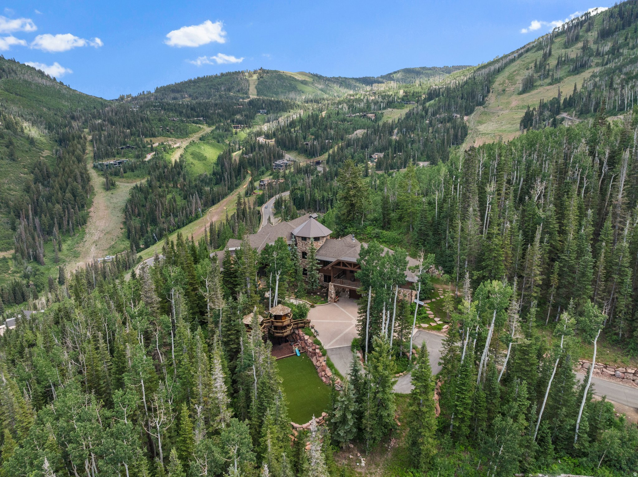 Welcome to a rare and remarkable mountain retreat, where unmatched privacy meets refined alpine living. Perched on one of the most desirable homesites in the exclusive Colony at White Pine Canyon, this five-bedroom, five full and four half-bathroom estate offers panoramic ski resort views, direct ski-in/ski-out access, and the ultimate in year-round mountain living. Spanning multiple levels and serviced by a central elevator, the home is designed with timeless mountain finishes-rich woodwork, natural stone, and vaulted ceilings that frame breathtaking alpine views. Every detail has been thoughtfully curated to balance elegance and comfort, creating a space that feels both grand and inviting. The main living areas flow effortlessly, from the formal living room with its statement fireplace and expansive windows, to a warm and intimate hearth room ideal for quiet mornings or aprs-ski relaxation. The spacious family room, complete with a wet bar, is designed for entertaining, while the dedicated media and recreation room adds a layer of fun and function. A private office provides a serene and productive workspace, and a separate workout room ensures wellness is always within reach. Outside, the living experience continues with a series of extraordinary outdoor spaces. Heated patios allow for year-round enjoyment, and the custom fire pit and oversized hot tub offer the perfect place to unwind beneath the stars. A large turf playing field welcomes family games and summer gatherings, while a whimsical children's playhouse-tucked into the trees-makes this retreat just as magical for little adventurers. With direct ski access from your doorstep, the home offers unmatched convenience for skiers of all levels. Whether you're heading out for first tracks or coming home for lunch by the fire, the mountain is quite literally at your feet. Set on 6.87 acres, surrounded by towering evergreens and untouched wilderness, the property offers total seclusion-your own private forest-while still just minutes from the world-class dining, shopping, and cultural offerings of Park City.  This is more than just a home. It's a place where generations will gather, adventures will unfold, and memories will be made for years to come. A private lodge. A year-round sanctuary. A mountain legacy unlike any other.