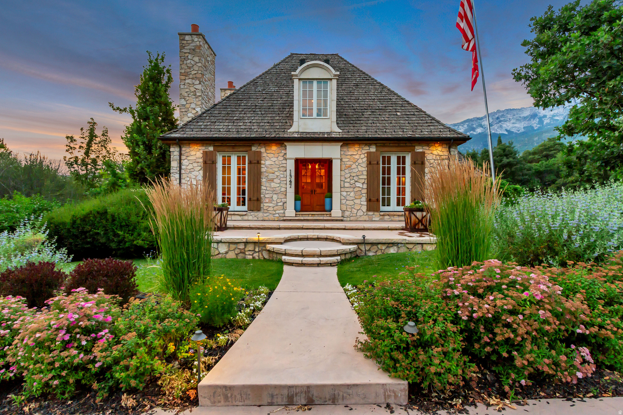Rooted in timeless French design and built with an unwavering commitment to quality, this waterfront Alpine estate is set along the banks of Dry Creek, creating a setting that is as rare as it is beautiful. Tucked at the end of a quiet lane and just moments from Lambert Park's extensive hiking and biking trails, the home offers exceptional privacy while remaining close to everything Alpine has to offer. A classic cedar shake roof, natural materials, and enduring craftsmanship define every space, where soaring ceilings, oak hardwood floors, marble finishes, and solid wood doors create warmth, scale, and character throughout. The kitchen was designed without compromise, featuring two oversized islands, a 60-inch Wolf range, double ovens, marble countertops, dual sinks, and an exceptional butler's pantry that functions as an extension of the kitchen rather than an afterthought. Radiant heat runs throughout the home, adding a level of comfort rarely found, while the thoughtfully designed lower level includes a private theater and walkout access directly to the banks of Dry Creek. Mature trees surround the property to create remarkable privacy. Whether enjoying the spa, watching kids play in the backyard, or simply listening to the creek from the patio, the outdoor setting becomes an extension of the home itself. An adjoining 0.89-acre parcel with a barn is also available for purchase.