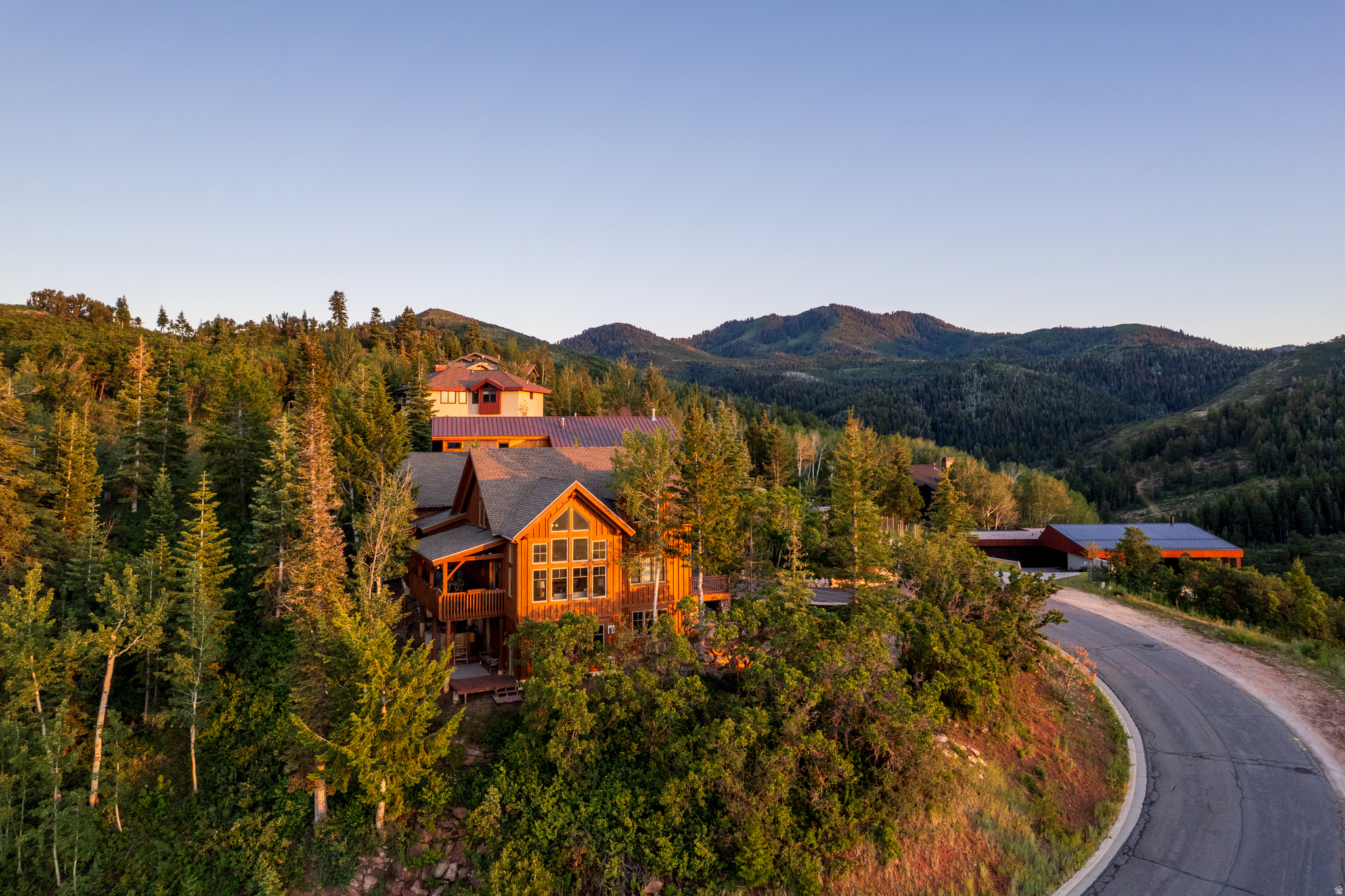 Welcome to 7141 Canyon Drive - where timeless craftsmanship, natural beauty, and modern luxury converge in perfect harmony. Tucked into the trees of the coveted Pineridge community, this stunning 4-bedroom, 4-bath timber-frame home isn't just a place to live - it's a place to breathe, to gather, and to be inspired. From the moment you step inside, you're greeted by soaring vaulted ceilings, century-old Douglas Fir beams, and floor-to-ceiling windows that capture sweeping views of Park City's mountains and valleys. Every detail tells a story - from reclaimed redwood decks once part of the Great Salt Lake Railroad, to the warmth of radiant-heated hardwood floors beneath your feet.  Designed with heart and soul, the open-concept layout invites connection - whether you're hosting a dinner party in the gourmet kitchen, unwinding by the fireplace in the great room, or stargazing from the hot tub on your private deck. A separate guest suite with its own kitchen, bath, and fireplace offers flexibility for visitors or extended family. Surrounded by towering spruce and white pines and backing directly to 140+ acres of open space and trails, this is more than just a home - it's a sanctuary. With low HOA dues, a spacious two-car garage, and a prime location just minutes from world-class skiing, golf, and dining, 7141 Canyon Drive offers a rare opportunity to live the Park City dream - with history, heart, and high-end comfort.