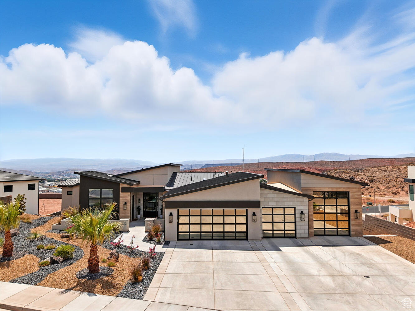 A designer-crafted sanctuary where every finish is curated and wide-open views make every sunset feel like it's yours alone. From this hilltop retreat, ride directly from your home to the Red Cliffs trails, explore the mountains, or unwind by your resort-style pool. Contemporary architecture and low-maintenance landscaping welcome you home. The front patio opens to a bright foyer and more than 5,000 square feet of designer-finished space. Warm alder trim, Rustica doors, custom grass-cloth walls, and art-quality lighting tie the interiors together. Every bedroom is en-suite, and with an optional furnishing package, you could have the whole home professionally decorated and move-in ready.  The floor plan puts your main living areas upstairs to take in the panorama over St. George and the mountains. The great room is open and comfortable, centered on a floor-to-ceiling fireplace and sliding doors to a wide view deck.  The kitchen is built for cooking and gathering, with a huge waterfall-edge island, top-tier appliances, and loads of storage. A bonus pantry adds a second sink and ice maker for every delightful concoction you create. Also upstairs, the primary suite frames miles of scenery and opens to the deck. A private sitting area offers space to unwind. The primary bath brings together stone and wood, an oversized shower, a freestanding tub, and thoughtful storage. A separate-entry casita on this level works as a guest suite or office, finished with custom wall coverings and its own full bath.  Downstairs expands your options even more. A quiet reading nook tucks under the stairs. The lower living room connects bedroom suites, a home gym, and private office, with walkout access to the covered patio and pool. A built-in bar with an ice maker and beverage fridge keeps snacks and drinks handy, alongside a nearby powder bath.  Outside is set up for all-day lounging and easy entertaining. The 18x31' saltwater pool is 4 ft deep with a shamu shelf, hot tub, and an integrated cover, all wrapped by a broad sundeck and privacy walls. An outdoor shower pavilion, shaded dining patio, turf lawn, and a large side yard make it simple to spread out. Sunset color pours across the mountains every evening. A 4-car RV garage holds ATVs, gear, and everything else you bring along. From your hilltop perch on the Middleton Black Ridge, you have direct access to the Red Cliffs Conservation Area and quick trips into town, the best of both worlds for trail days, quiet nights, and easy hosting. The perfect mix of design, function,and location, ready for what you love to do