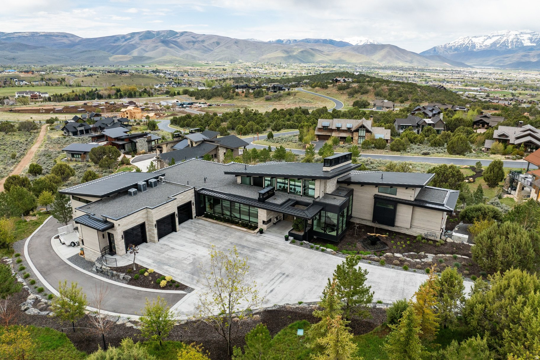 This custom architectural masterpiece, designed by Michael Upwall and built by Phelps Construction, sits on 1.93 acres with stunning west-facing views of Mt. Timanogos. Access is available to a full golf membership at Red Ledges with deposit. The residence showcases commercial-grade construction with full-stack imported stone, custom metal trim, and a two-dimensional roof that maximizes the property. Oversized hallways and doorways, an elevator, and 12' lower-level ceilings provide exceptional quality and accessibility. Inside, the dramatic great room features floor-to-ceiling windows, white oak flooring, invisible surround sound, and a striking full-length concrete and steel hearth fireplace. The gourmet kitchen offers Wolf, Sub-Zero, and Cove appliances, including a 60'' dual-fuel range, flowing into 1,100 sq ft of covered al fresco dining with a Wolf outdoor kitchen, gas firepit, and soft-serve ice cream machine. The lavish master suite includes a steam shower, sauna, free-standing tub, and massive custom closet system. Additional highlights include a 12-seat theater with premium sound system, fully equipped gym, and multiple guest suites. Outdoor living is resort-style with a 22' x 65' saltwater pool and spa, large jacuzzi, three outdoor fireplaces, maintenance-free artificial turf, golf practice green, ax throwing, outdoor bed swing, and bespoke water feature. The property includes a fully automated sprinkler/fertilization system and over 100 mature trees. Additional premium features include a massive 10+ car garage (1,900 sq ft main + 1,200 sq ft lower with lift), both heated with polyurea flooring and EV charging, plus a Fort Knox vault. Other luxuries: whole-home Generac generator, 360 surveillance, commercial fire suppression, five HVAC units with purification, heated driveway, hidden trailer pad, and full Control 4 automation. Luxury lives here.