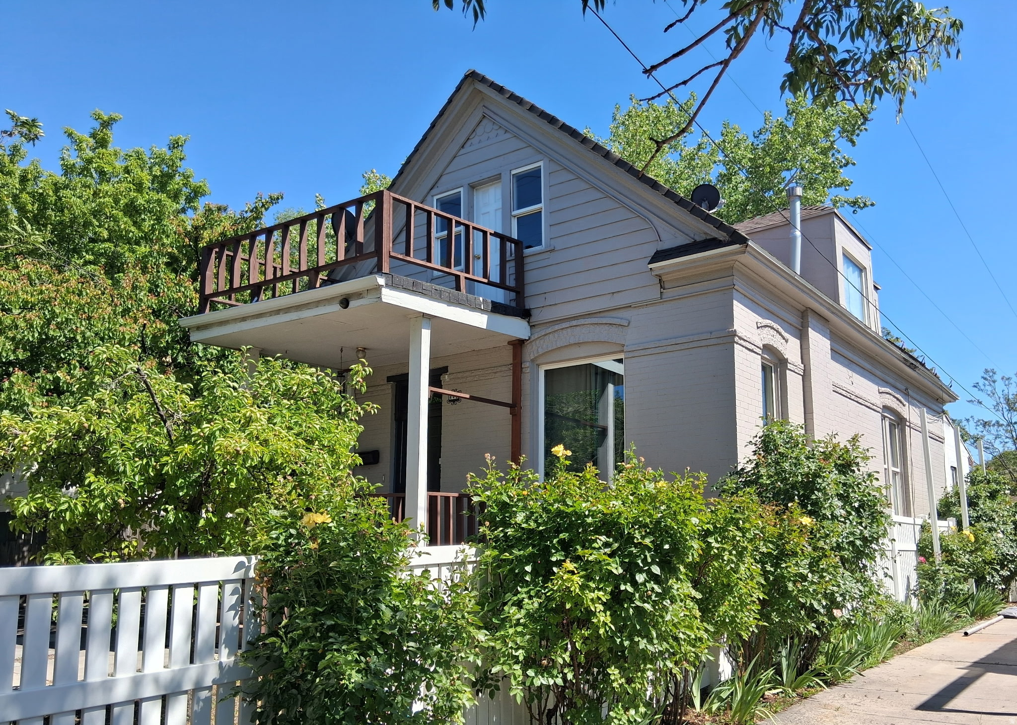 Built in 1896 and full of original character, this 4-bedroom, 2-bathroom bungalow-style home at 442 E 800 S in Salt Lake City offers 1,807 total square feet across three levels - including a main floor, upper level, and partial basement - all situated on a rare 0.19-acre lot that is exceptionally rare for this location and price point in the city. The brick exterior, covered front porch with classic columns, grand staircase with an original white-painted balustrade, crystal chandeliers, and quality throughout speak to the era's craftsmanship, while the home has been thoughtfully maintained and updated for modern living. The main level features a spacious formal living room with high ceilings, a dedicated dining area, and a kitchen equipped with a gas range, dishwasher, tile flooring, and updated cabinetry with ample storage. The upper level provides two additional bedrooms, a fully updated three-quarter bathroom with a glass-enclosed shower stall and new vanity, a newly added kitchenette, and access to a private upper deck with tree canopy and mountain views - a truly rare outdoor space for an in-city property of this type. The main floor also includes two well-proportioned bedrooms with good closet space and natural light, along with a full bathroom. The partial basement offers additional storage and utility space. Out back, the property shines with a covered rear porch perfect for entertaining, a large concrete patio, a substantial 300-square-foot outbuilding/shed, mature fruit trees, and a fully fenced, expansive yard that offers privacy and flexibility that is hard to find within the city limits. The home has central forced-air heating, central air conditioning, an asphalt shingle roof, and a concrete driveway with parking for up to four vehicles. This home has recently been inspected, and virtually all identified deficiencies have been corrected - making it genuinely move-in ready and reducing the risk and uncertainty that typically accompanies a home of this vintage.  Located in the highly sought-after Liberty Wells neighborhood, it sits within blocks of Liberty Park - one of Salt Lake City's largest and most beloved green spaces - and just minutes from the vibrant 9th & 9th district, with its independent restaurants, coffee shops, and boutiques, as well as easy access to downtown Salt Lake City, the University of Utah, Sugarhouse, and Interstate 15. The area is well served by public transit. For buyers seeking original historic character, a large lot, functional multi-level living, and a location that puts the best of Salt Lake City within easy reach, this property represents outstanding value and a rare opportunity in today's market. If the square footage or acreage of the property or improvements is of material concern to the buyer, the buyer is responsible for verifying the square footage/acreage measurements and improvements to the buyer's satisfaction.
