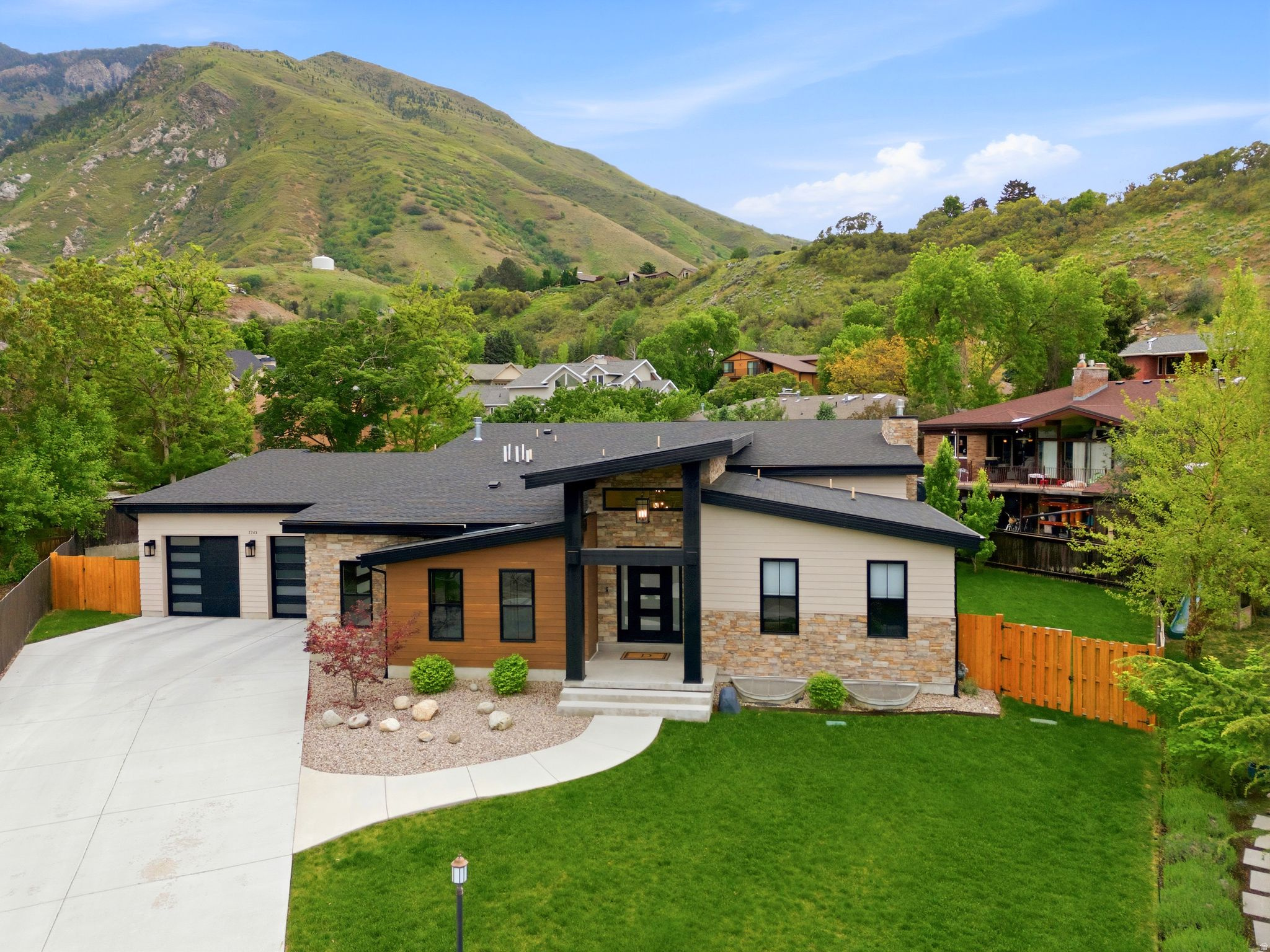 This striking modern custom home set against the foothills of the Wasatch in Cottonwood Heights is thoughtfully designed. Soaring vaulted ceilings, clerestory windows, and a dramatic floor-to-ceiling stacked-stone fireplace anchor the great room to a kitchen made for cooking and entertaining.  A butlers pantry makes entertaining effortless and keeps the main kitchen pristine. Built in 2022, it has both elegance and functionality in mind. Off the front entrance, find a perfect space for an office (or guest bedroom) with en suite.  Enjoy the large dining nook framed by canyon views through black-framed windows.  The master suite doesn't disappoint with its own views, large walk-in closet with bench and built-in shelving, oversized double headed shower and free standing tub.  The finished lower level is its own residence within the home: an expansive secondary great room with its grand kitchenette. More custom lighting, a black window package, another stacked stone fireplace, a 2nd laundry room, 2 junior suites and 2 additional bedrooms with a shared bath.  The oversized garages have customized epoxy floors. There is also a secured storage room with a vault door.  A rare opportunity to own a newer home in an established area desirable for being able to walk to restaurants and have easy canyon and freeway access.
