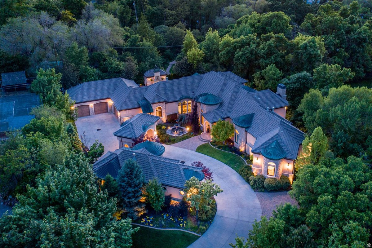 Tucked away on a private, tree-lined lane in Holladay, this resort-style estate offers rare privacy in a picturesque setting with an exceptional array of amenities. Situated on 1.15 acres with sweeping mountain views, this beautifully updated home blends timeless architecture with refined, modern living. The main level features an elegant living room, formal dining, and a stunning, beautifully designed kitchen offering generous workspace, abundant cabinetry, and quality appliances, all flowing seamlessly into inviting gathering areas. A striking office with walnut ceilings, flooring, and woodwork.  The main-level primary suite is a peaceful retreat, capturing beautiful mountain views and featuring a spa-inspired bath, dual closets, glass-encased vertical flame columns and a private deck. Expansive retractable doors open to a spectacular outdoor setting with a saltwater pool with water features, spa, and outdoor BBQ area surrounded by mature landscaping. The lower level features high ceilings, three spacious bedrooms, three baths, a theater, a home gym, a wine gallery, and a game lounge. A detached private guest house offers its own kitchen, family room with a two-sided fireplace, large bedroom, and spa bath, ideal for extended stays or private guest accommodations. Gated and impeccably landscaped, the grounds showcase stunning mountain views and a sense of seclusion, just minutes from multiple hiking and biking trails, world-class skiing, shopping, dining, and golf.. Expertly constructed by Dan Stewart, Tri-City Construction.