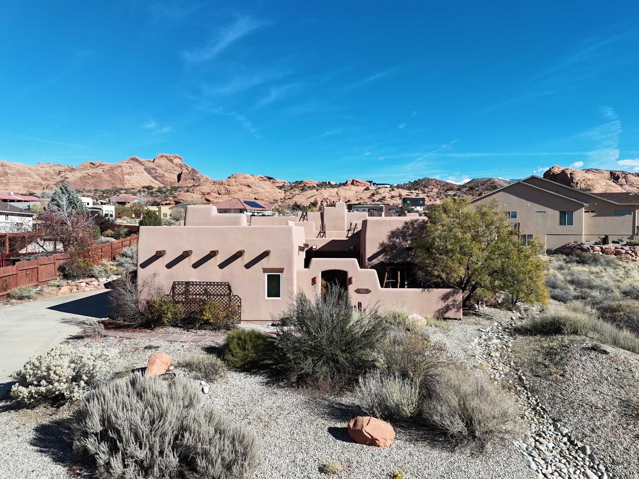 Beautifully crafted adobe-inspired home featuring authentic viga ceilings, warm natural textures, and a classic kiva fireplace. The open living and dining areas flow effortlessly, offering abundant light and inviting Southwestern character. Enjoy a spacious covered patio with flagstone flooring, mature desert landscaping, and serene views of the surrounding cliffs. The walled courtyard provides privacy while maintaining a strong connection to the red rock scenery. Located in a quiet neighborhood close to Moab's outdoor recreation. Home furnishings and dcor are negotiable.