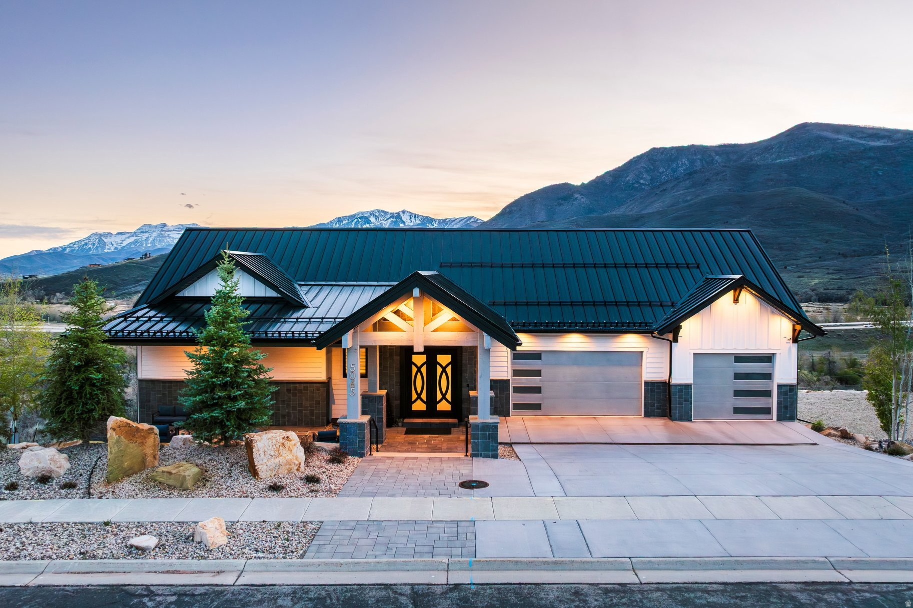 This light-filled, one-of-a-kind custom home stands apart with its beautiful designer finishes and contemporary style. Located on the south end of Jordanelle Reservoir, just minutes from the new Deer Valley East Village, it offers sweeping panoramic views from every level of Deer Creek Reservoir, Mount Timpanogos, the new Runs at Deer Valley, and the Provo River. Designed for entertaining, the open floor plan features huge windows, a gorgeous fireplace, and seating for 30+ guests. The chef's kitchen includes double ovens, both gas and induction cooktops, and a large hidden walk-in butler's pantry. A spacious deck off the kitchen adds outdoor living with a gas BBQ, fireplace, and TV.  The main-floor primary suite offers two walk-in closets (one with stackable washer/dryer) and a spa-like ensuite with backlit onyx countertops, custom heated shower and soaking tub. The lower level includes an additional kitchen, fireplace, dining area, and patio with stunning views, plus four spacious bedrooms and three bathrooms. A dedicated wellness retreat features a cold plunge, infrared sauna, fitness room, and golf simulator.