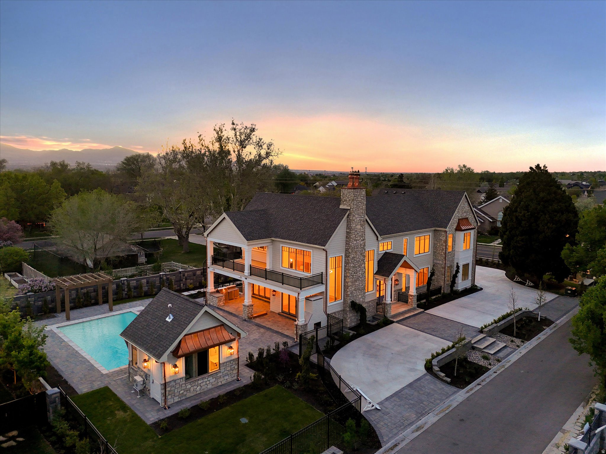 Set within the prestigious Viking Court subdivision, this newly constructed residence by the highly regarded Silverhawk offers a rare expression of modern luxury-where scale, craftsmanship, and livability come together in a way that feels both commanding and considered. From the moment you enter, the home reveals itself with intention. Soaring 10'20' ceilings and expansive light-filled volumes create an immediate sense of scale, while wide-plank White Oak flooring and custom White Oak beam detailing ground the architecture in warmth and texture. Every finish feels deliberate-elevated, but never overstated. At the center of the home, the kitchen acts as both anchor and gathering point. Custom inset cabinetry, striking quartzite surfaces, and seamless connectivity to the surrounding living and dining spaces create a natural rhythm for both everyday living and elevated entertaining-equally suited for quiet mornings or full-scale gatherings. The main-level primary suite is its own private retreat. Direct access to a covered patio extends the space outward, while the spa-inspired ensuite introduces a more refined pace of living-an oversized walk-in shower, freestanding soaking tub, heated tile floors, and a beautifully built-out closet with integrated laundry, designed with both function and ease in mind. Upstairs, four generously sized ensuite bedrooms offer privacy without compromise-each thoughtfully designed with custom closets and an emphasis on comfort, proportion, and light. The lower level continues the experience at a different scale-bright, open, and intentionally flexible. Light wells bring in natural illumination, creating a space designed for both entertainment and adaptability, whether envisioned as a theater, golf simulator, or expansive gathering space. And then there is the connection to the outdoors-where this home fully opens up. A fully retractable pocket door dissolves the boundary between inside and out, leading to an extraordinary covered paver patio that spans the entire south side of the home. This resort-inspired space is fully realized, with dedicated dining and lounge areas, a complete outdoor kitchen, and direct access to a stunning pool with integrated spa and a private pool house-creating a true extension of the home rather than a separate experience. The grounds are designed to match the architecture in both scale and intention-professionally landscaped, fully fenced, and framed by a paver driveway and grand entry sequence. An oversized 6 car garage completes the property, offering exceptional space for vehicles, storage, and lifestyle flexibility. This is a home that doesn't simply offer luxury-it defines it. A statement residence where design, function, and experience align in one of Draper's most sought-after settings.