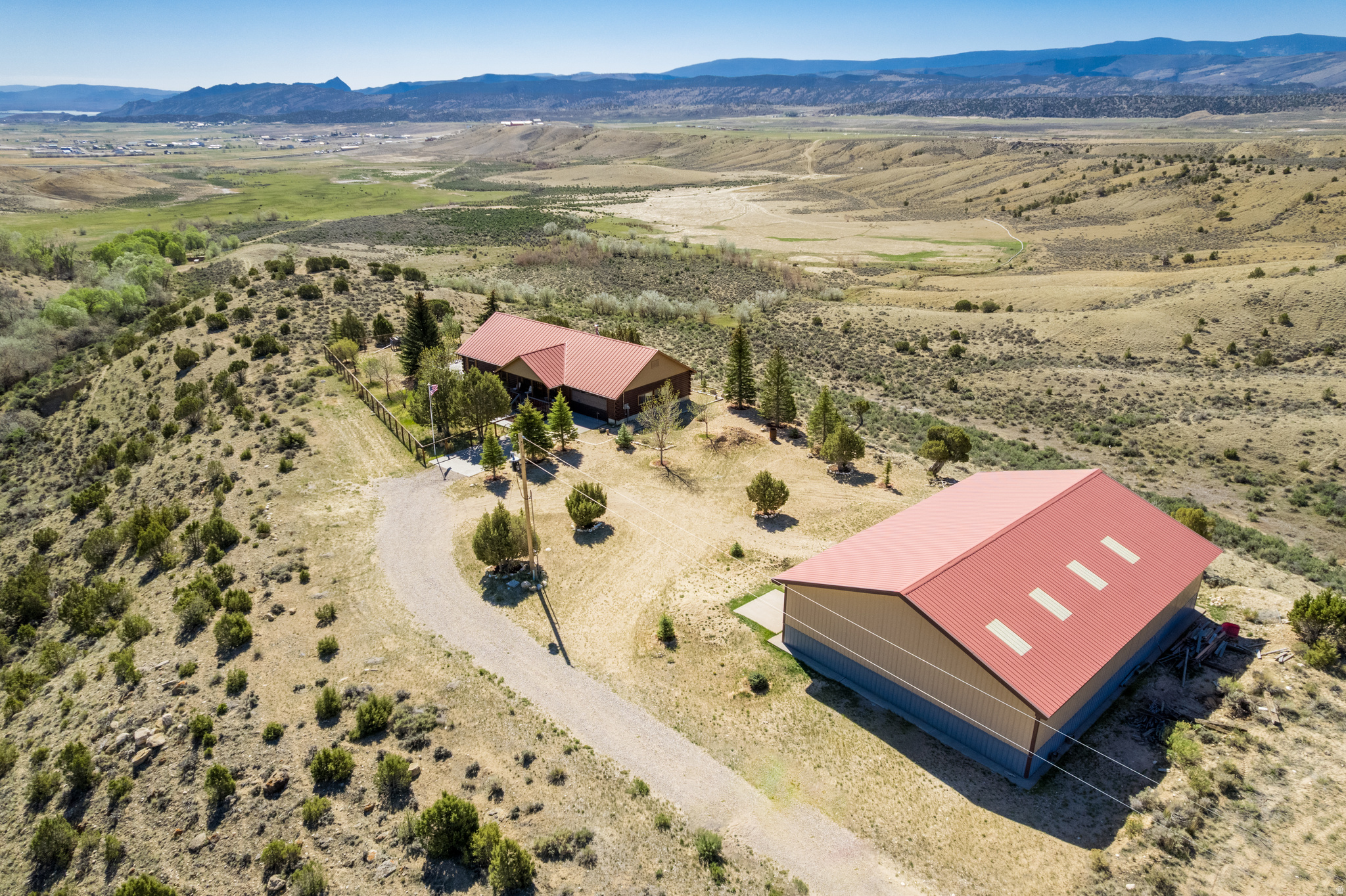 Beautiful 3-acre property with coveted lake, valley, and mountain views near Flaming Gorge. This well-maintained 3-bedroom, 3-bath home offers privacy, tranquility, and room to enjoy the outdoors. Watch the sun rise over the lake from the expansive wraparound deck, or relax on the covered porch overlooking the fenced front lawn with mature shade trees. Be the gathering place for friends and family with plenty of space to park RVs, boats, and recreational toys. Inside, the spacious family room features a cozy wood-burning stove, while the finished basement offers an open layout with a bathroom, abundant storage, and plenty of space for games and family gatherings. A massive 40' x 60' (10' garage doors) shop/garage provides ample room for boats, RVs, storage, hobbies, and projects. Located at the end of the road on the point, this peaceful retreat is just minutes from Flaming Gorge and endless boating, fishing, hunting, and outdoor recreation.  Call agent for a private showing. Square footage figures are provided as a courtesy estimate only and were calculated from exterior dimensions. Buyer is advised to obtain an independent measurement.