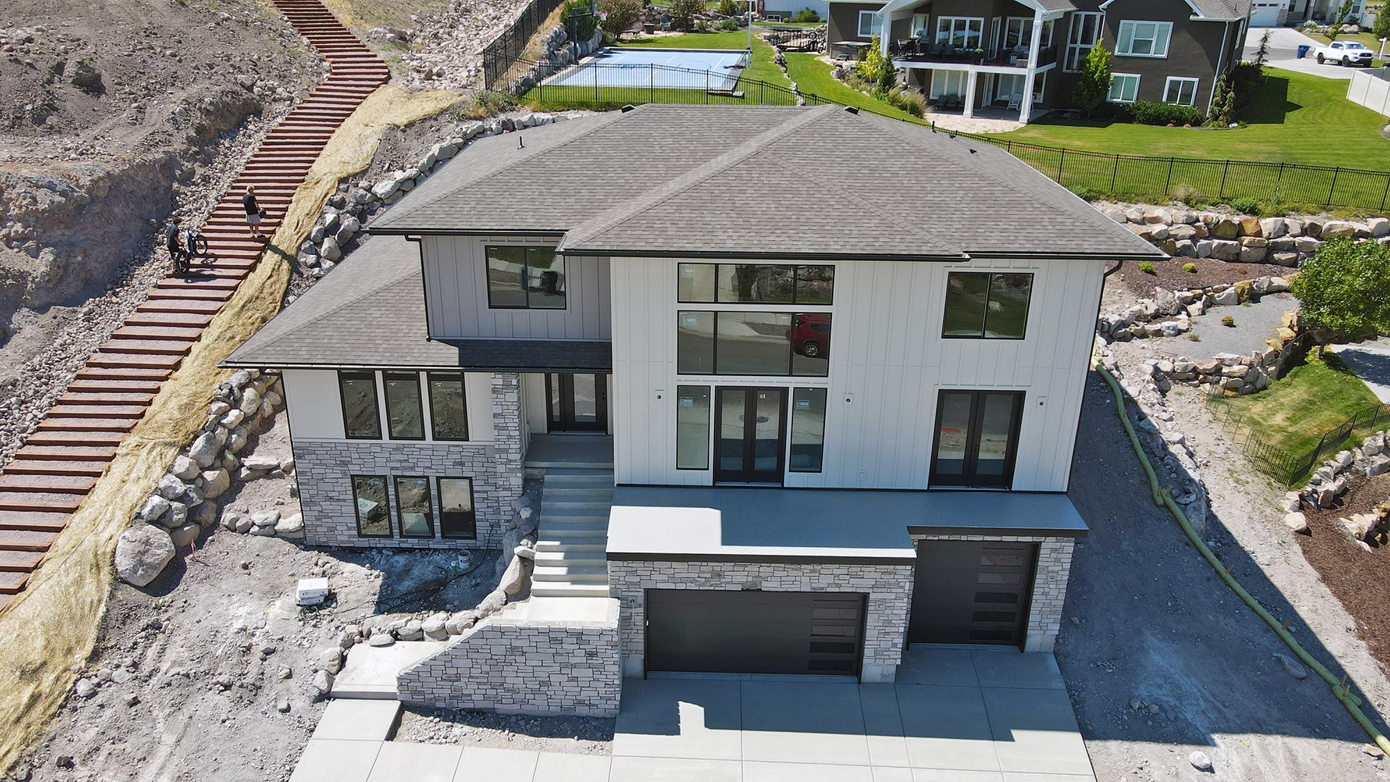 5 beds. 5 baths. 4,833 sq. ft. across three levels. And views that earn their own line. Perched in Eastridge Herriman - one of the only hillside positions in the Salt Lake Valley with unobstructed sight lines to both the Wasatch Range and the Oquirrh Mountains - this 2026 new build doesn't ask you to imagine the lifestyle. It just shows you. The main floor is designed around the way people actually live. A two-story great room floods the space with natural light and a sense of scale that most homes at this price point still can't deliver. The main-floor primary suite keeps things easy - no stairs before coffee. The kitchen, the dining, the walkout deck access - all of it connected, all of it positioned toward the view. Upstairs, four additional bedrooms and bathrooms give you room for the kids, guests, a real home office - not a converted closet. Downstairs, 10' ceilings and serious finish potential mean the lower level isn't an afterthought. It's future equity, already framed. The oversized 3-car garage with 12' ceilings handles the cars, the gear, and the weekend toys. Because at this address - six ski resorts within 45 minutes, Blackridge Reservoir five minutes away, 60+ miles of Herriman trails at the community edge - you're going to need the storage. Eastridge Herriman is the highest-elevation new construction community in the southwest Salt Lake corridor, positioned above the valley inversion, twenty minutes from Silicon Slopes, and ten from The District's retail and dining. It is not a subdivision that happened to land on a hillside. It was built for this hill, on purpose.