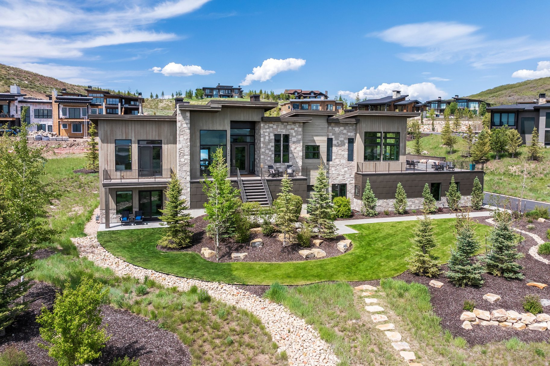 Discover this fabulous 5-bed home in Deer Vista, just 12 minutes from the heart of Park City and a quick drive to Deer Valley Resort East Village. Blending luxury mountain living with the warmth of a true neighborhood community, 140 W Vista Ridge offers 5,842 square feet of thoughtfully designed space where unforgettable gatherings, outdoor adventures, and everyday comfort come together effortlessly. Filled with natural light and framed by stunning mountain views, this mountain contemporary home welcomes family and friends with five spacious en-suite bedrooms, expansive entertaining areas, and a seamless flow designed for both relaxation and celebration. At the heart of the home, the open concept chef's kitchen is made for connection, featuring a spacious central island, pantry, and plenty of room for everything from casual breakfasts before hitting the slopes to memorable dinner parties with friends and family. The spectacular rooftop deck showcases panoramic mountain vistas and provides the perfect setting for morning coffee, sunset cocktails, and stargazing under Utah's clear skies. Working from home feels anything but ordinary with inspiring views around every corner. When it's time to unwind, enjoy movie nights in the dedicated home theater. An oversized 4-car garage with EV charger offers abundant space for vehicles, outdoor gear, and all the essentials that come with an active mountain lifestyle. Whether you're searching for a full-time residence or the ultimate mountain getaway, this home offers the flexibility and comfort to fit every season of life. Located within the sought-after Deer Vista community of just 104 homesites, neighbors quickly become friends. A short stroll leads to the community park, where residents gather for dog walks, happy hours, holiday picnics, and monthly book club chats. It's the kind of place where luxury living meets genuine connection.