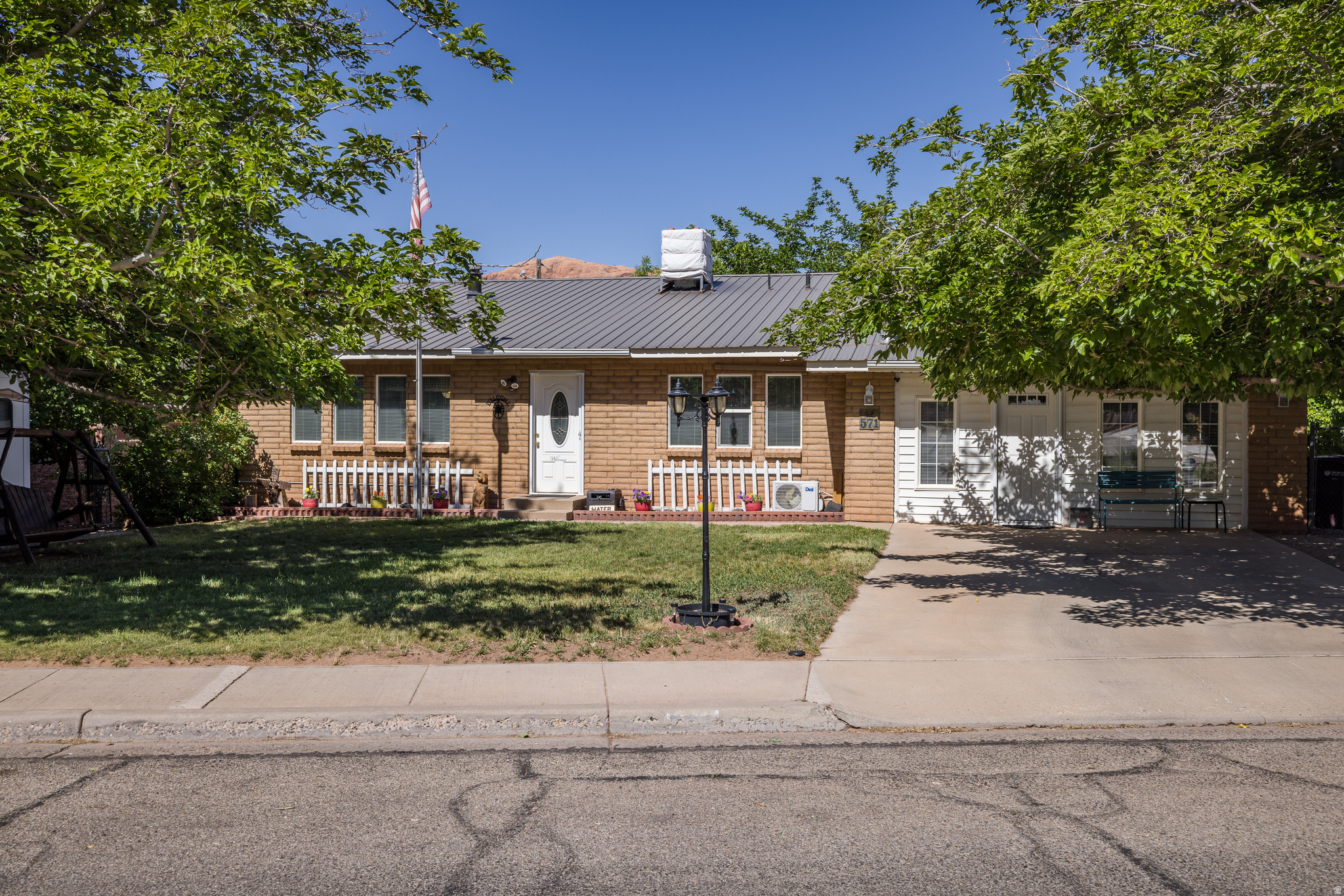 This solid brick home has a functional layout that improves upon the traditional split-entry design by welcoming you directly into the main-floor living room before transitioning between levels. The interior features three bedrooms, three bathrooms, and updated LVP flooring throughout. Climate control is highly versatile, utilizing a mini-split system for heating and cooling, supplemented by three gas fireplaces and a backup evaporative cooler. A notable feature is the estimated 480-square-foot garage conversion that the owners had used as a mother in law suite with its own bathroom, its own heating and cooling, entrance and private deck. The lower daylight basement level provides a dedicated bonus room, currently utilized as a craft space, and an expansive storage area that spans the entire width of the home behind half-height access doors. The fully fenced backyard includes a private upper deck located off the guest suite offering direct views of the Portal, a covered lower patio accessible from the basement, 6 mature shade trees, a pear tree, two apricot trees, automatic sprinkling system, and extensive storage including three interconnected sheds and one standalone unit. For those with additional equipment, the property includes RV parking and a spacious backyard with ample room to construct a detached shop or garage. Situated in a prime location, the property is adjacent to local schools (one side of the property sharing the schools concrete fence) and provides immediate access to the bike trail system located just across the street. Its proximity to Arches National Park, the city park, and downtown festivities makes it an ideal hub for enjoying the area's unique recreation and community events. Square footage figures are provided as a courtesy estimate only.  Buyer is advised to obtain an independent measurement.