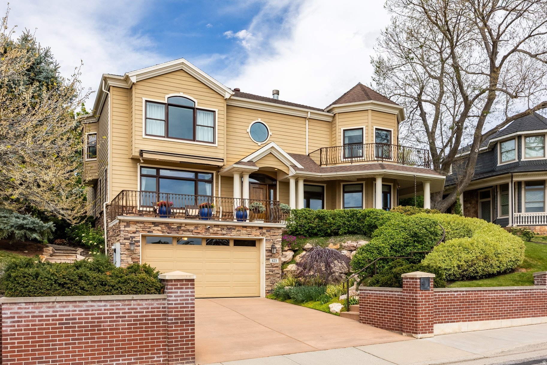 Experience luxury and easy effortless living in this spectacular, masterfully designed home located in the highly desirable Capital Park community in the high Avenues. This exceptional residence, built in 2001,  defines luxury living with timeless architecture, and impeccable craftsmanship. Featuring a welcoming front porch framed by mature landscaping and a dramatic two-story entry, this home shines with rich hardwood floors across the main level and an inviting floor plan. A stunning kitchen boasts pristine stone countertops, warm butcher block bar counters, ultra-luxury appliances, two dishwashers, a warming drawer, walk in pantry and eat-in kitchen nook. The sophisticated layout offers a seamless flow into the living room area, complete with a fireplace and amazing views that you only get in the high Avenues. The main floor also features a convenient powder room, a picturesque view filled living room and office with elegant French doors leading to a wisteria covered pergola and an attached bath making it suitable for an ensuite bedroom if desired. The upper level offers a magnificent view inspired primary suite with turreted sitting area, fireplace, walk-in closet, soaking tub, steam shower and private deck. Upstairs, two additional generously sized bedrooms, with an adjoining bath, offer an effortless living and flexible layout. The fully finished lower level is an entertainer's dream with a theater room with custom built-ins, newer 100 inch screen, a bar, wine cellar, a full bath, a bedroom and storage/workshop. Outside, relax on the beautiful patio and professionally thoughtfully landscaped yard overflowing with color. Set against a backdrop of lush gardens, mature plantings, and classic stonework, the grounds offer an intimate setting perfect for alfresco dining or a quiet morning coffee.  An attached garage with parking for three cars flows into a large mudroom with custom lockers. Experience resort-style living every day within a home that reflects uncompromising quality, enduring design, and gracious curb appeal.