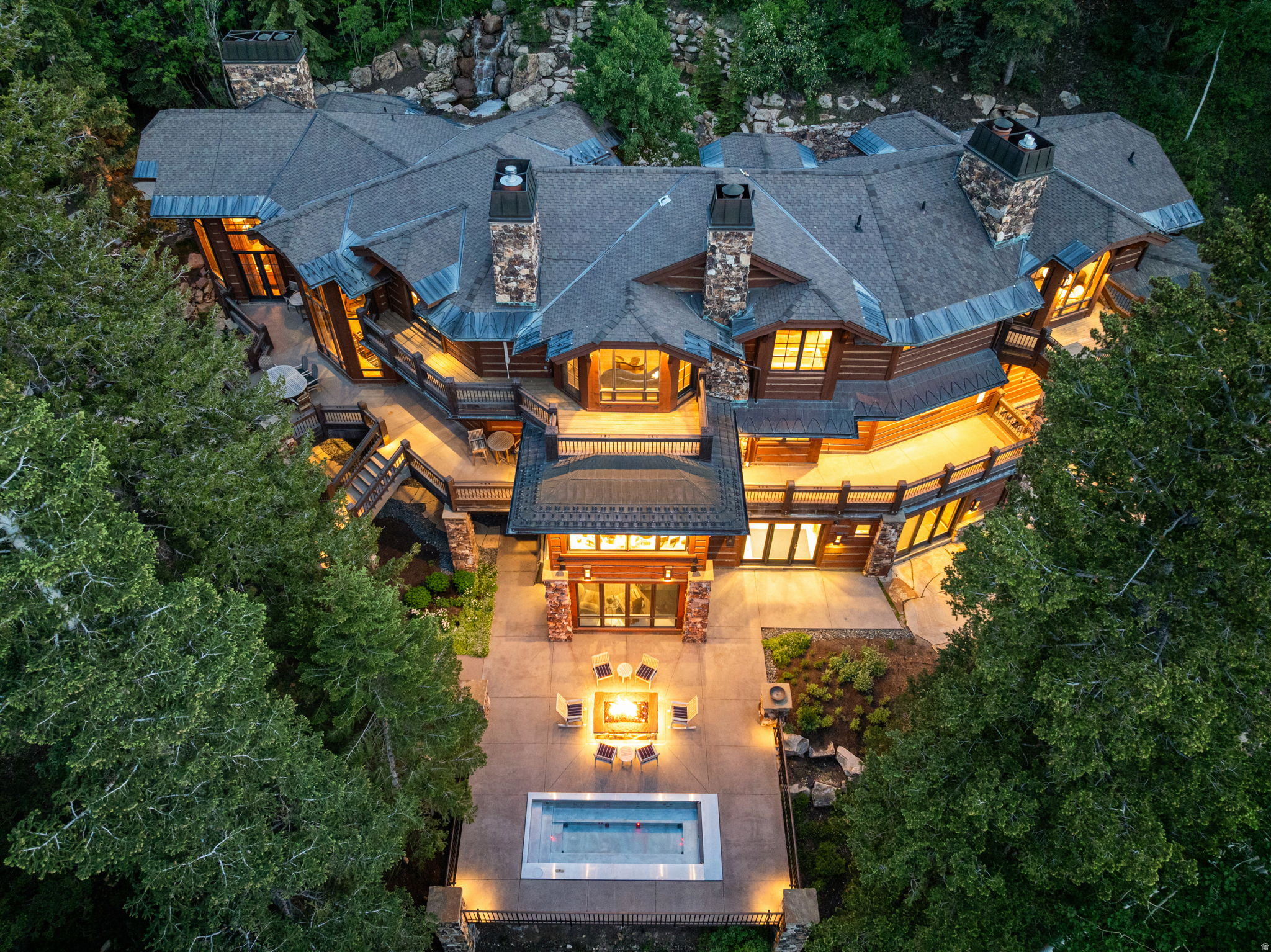 The closest ski-in/ski-out estate to The Colony gatehouse currently available, 22 White Pine Canyon Road, offers unrivaled privacy, accessibility, and turnkey mountain luxury in one of Park City's most coveted locations. Designed by the renowned Otto-Walker Architects and set on over five pristine acres at 7,600 feet elevation, this architectural retreat blends timeless alpine elegance with modern sophistication.  Just three minutes from The Colony's private entry gate, the property offers exceptional access to town and travel, while still feeling worlds away. A dramatic stone bridge leads to a fully snow-melted driveway, flanked by a cascading waterfall and a serene summer pond. Inside, natural textures and refined finishes unfold across more than 11,000 square feet of living space, recently refined with thoughtful interior enhancements and fully furnished by the award-winning Iluminus Group for a modern, inviting, and move-in-ready feel.  At the heart of the home is a newly completed chef's kitchen featuring La Cornue and Miele appliances, a walk-through butler's pantry, and informal dining surrounded by forested views. A custom-designed bunk room with six queen beds and a fully integrated ski lounge enhances the home's year-round functionality. Highlights include direct ski-in access and board-out convenience to the Tombstone, Timberline, and Over & Out lifts, two spacious primary suites, multiple grand family rooms, and a private study. Baths are well-appointed with curated stonework, bespoke faucetry, and spa-level fixtures throughout. A custom 20-person stainless steel hot tub with automatic cover anchors the outdoor experience, while a 4K home theater and dedicated gym with infrared sauna and steam room round out the wellness and entertainment offering. Cutting-edge Savant automation manages lighting, audio, climate, and security, and the home is finished with expansive terraces, two fire pits, and a four-bay garage built for cars, bikes, and mountain gear.  Step outside to access a network of hiking, biking, and snowshoeing trails. Or reach Park City's Historic Main Street in just 15 minutes for fine dining, shopping, and arts. Salt Lake City International Airport and private FBOs are just 40 minutes away, ensuring effortless arrival no matter the season.  Offering a rare balance of seclusion, style, and convenience, this is more than a luxury home, it is an invitation to live fully immersed in the best of Park City.