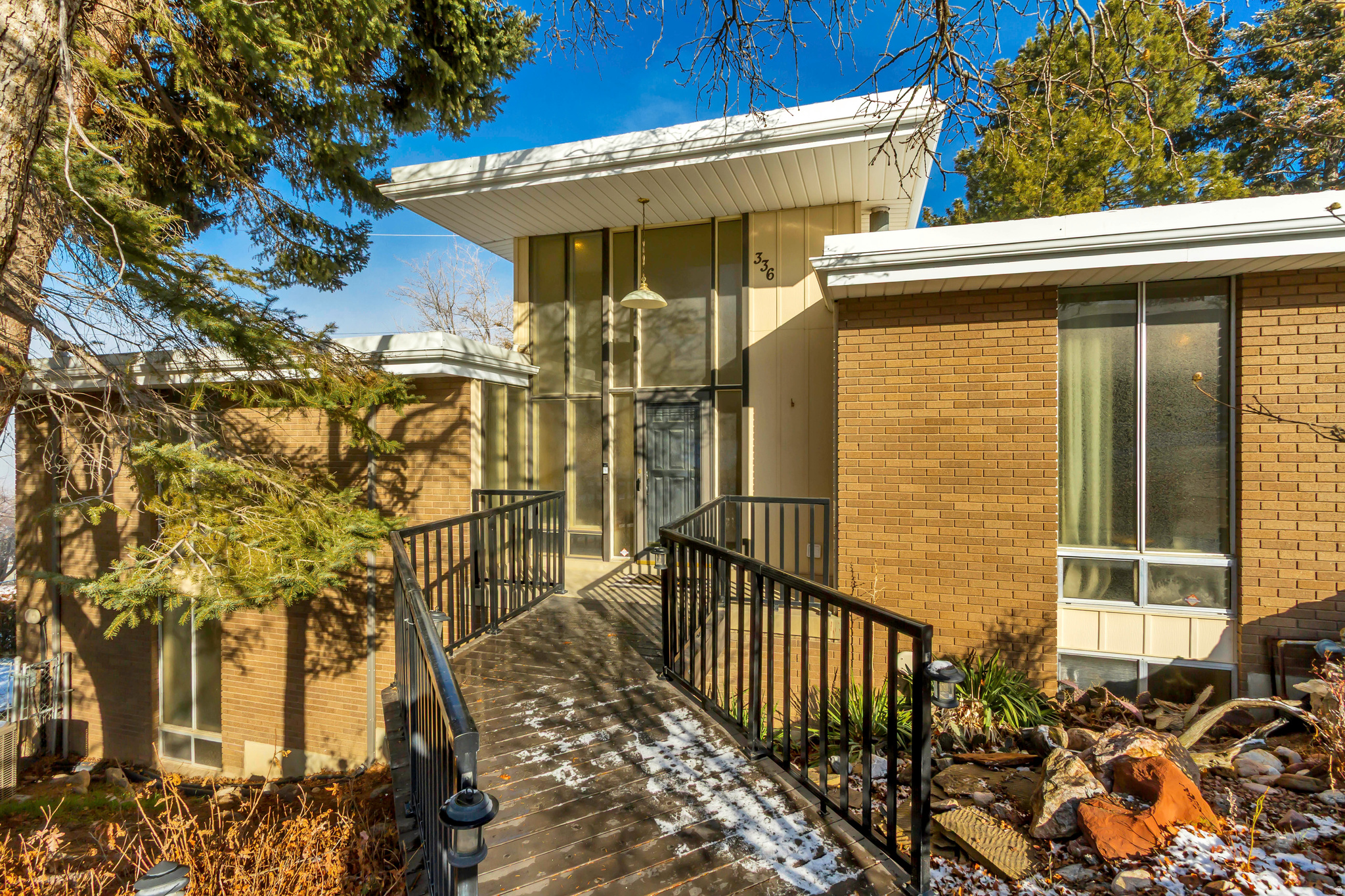 Step into a stunning mid-century modern gem thoughtfully inspired by Frank Lloyd Wright. This one-of-a-kind home showcases classic mid-century lines, soaring structural double trusses and a seamless blend of architectural charm with modern updates.  Recently renovated, the home features designer paint, new carpet, authentic oak hardwood flooring, durable luxury vinyl plank flooring in the basement, a new water heater, updated plumbing, and updated electrical. A functional mudroom addition and butler's pantry enhance everyday living, while two laundry hookups (stackable washers and dryers included) offer flexibility and convenience. With 6 bedrooms and 4 bathrooms, (2 walk-in showers) two main suites with en-suite bathrooms, two fully equipped kitchens, and oversized closets, this home provides exceptional space for comfortable living, entertaining, or multi-generational needs.   The cold storage features custom shelving crafted from vintage bleachers sourced from a local high school, adding a piece of local history and character.  The home contains Authentic mid-century slat accents throughout, original planter box on entry and a beautifully restored original conversation pit creating a stunning focal point that celebrates true mid-century entertaining and design.  Featuring an oversized covered carport designed to comfortably accommodate up to four vehicles, offering excellent protection from the elements while maintaining the home's authentic architectural style. Complementing the property is a fully insulated shed equipped with electricity and built-in shelving, providing outstanding space for hobbies, storage, workshop use, or creative projects.  Stretching the full length of the home, the back porch frames breathtaking views, while expansive windows capture unforgettable sunsets from nearly every angle. Nestled on Bountiful's coveted East Bench This rare mid-century treasure combines timeless design, thoughtful updates, and functional versatility in a highly desirable setting