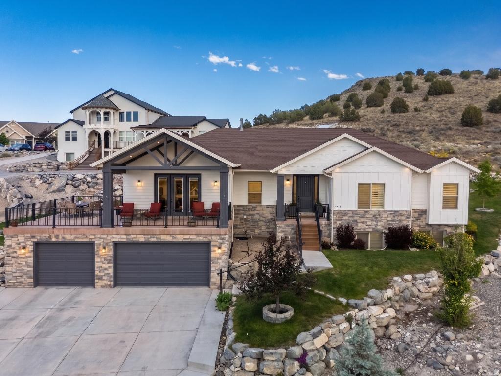 Tucked into the foothills of the Ranches of Eagle Mountain, this custom home delivers main-level living, multigenerational flexibility, and views you have to see to believe. Set on a rare .78-acre lot backing directly to BLM land, you will never have backyard neighbors here. The open space behind the home leaves room for pickleball courts, outdoor entertaining, or simply keeping it wide open.  Inside, the main level centers on a bright kitchen with quartz counters, custom alder cabinetry, a gas range, and a large center island. Vaulted ceilings with exposed wood trusses run through the kitchen and dining areas. Step out the kitchen french doors onto an enormous covered and uncovered patio that takes in sweeping mountain and valley views, with sunsets to match. The living room features a gas fireplace flanked by custom built-in shelving, and a dedicated office gives you a quiet place to work from home.  The primary suite offers a comfortable retreat with plenty of natural light. Throughout the home you will find quartz in the kitchen and bathrooms, plantation shutters on the windows, two laundry rooms, a theater room, and cold storage with built-in shelving.  The standout feature is downstairs. A complete second living space includes its own kitchen, living area, bedrooms, bathroom, and laundry, perfect as an ADU or mother-in-law suite. It sits right off the garage entry, making true main-level living possible for extended family or rental potential. The basement also includes a full-size theater room and a large workshop with epoxy flooring, with the same durable epoxy finish carried into the oversized three-car garage.  Add upgraded landscaping, a spacious driveway, and a hillside setting that puts those views front and center, and you have a home built for the way real families live. No HOA!! Close to several parks, miles of on and off-road trails, a bike park, restaurants, fast and fast-casual dining, grocery stores, and shopping. Square footage figures are provided as a courtesy estimate only and were obtained from public record.  Buyer is advised to obtain an independent measurement.