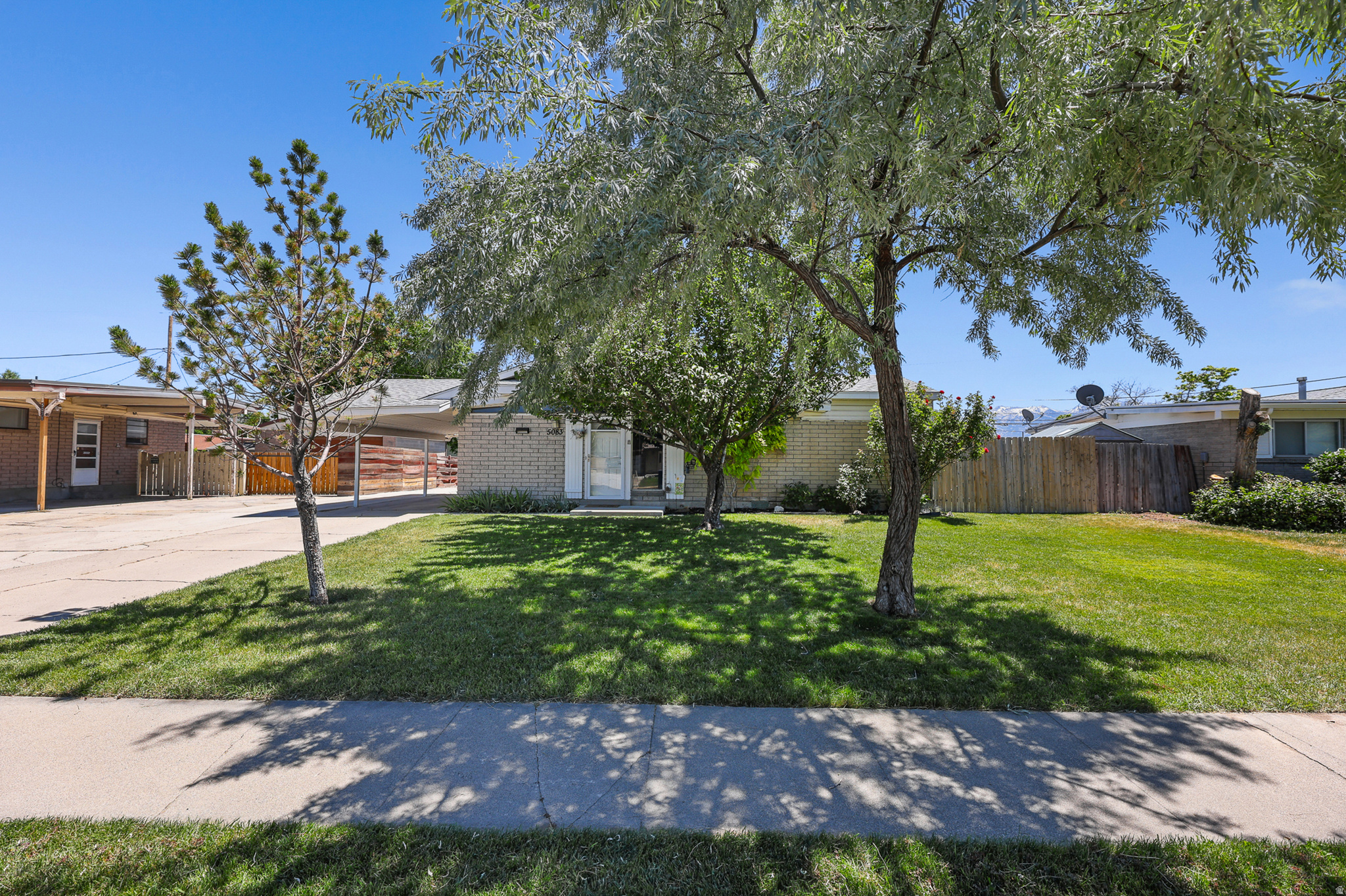 Discover the timeless appeal of this well-maintained mid-century modern home. Featuring 3 bedrooms and 2 baths, the spacious open-concept floor plan offers seamless flow between the living room and kitchen, highlighted by a striking exposed wood beam that showcases the home's character and charm. A bright sunroom provides the perfect space to relax and enjoy every season.  The property features an oversized detached heated 2-car garage, carport, and ample parking. Outside, you'll find a fully fenced backyard with a covered patio, storage shed, gardening area, and an extended driveway with plenty of room for an RV, trailer, or recreational vehicles.  Ideally situated near Vista Park, Taylorsville High School, Salt Lake Community College, shopping, and dining, this home also offers quick access to Redwood Road and I-215 for an easy commute. Combining comfort, functionality, and convenience, this is a property you won't want to miss.   Square footage figures are provided as a courtesy estimate only and were obtained from appraisal.  Buyer is advised to obtain an independent measurement.