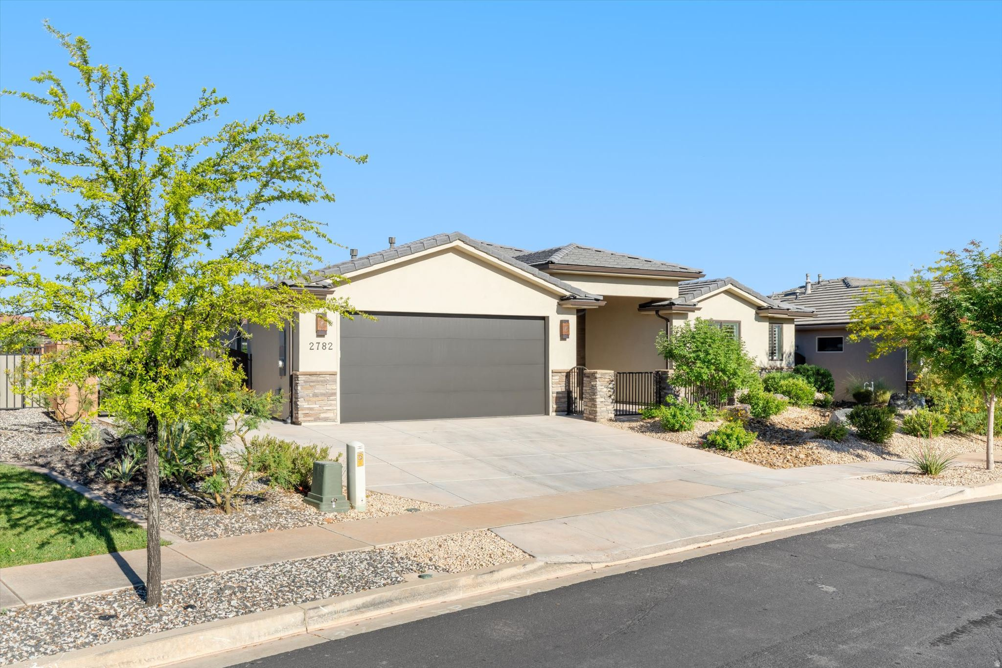 This beautifully designed single-level home offers 4 bedrooms, 2.5 baths, and 2,304 sq ft of thoughtfully crafted living space. Engineered wood flooring runs seamlessly throughout the home, adding warmth and a high-end finish. The open great room features 11' ceilings and an upper-end gas fireplace, flowing into the gourmet kitchen with quartzite countertops, ceiling-height cabinetry, under-cabinet lighting, a large island with storage, farmhouse sink, gas cooktop, wall oven, and a spacious pantry. Additional features include on demand hot water, R50 insulation (including the garage), and tile flooring in the bathrooms and laundry. Take in the red rock views from the dining room, primary bedroom, and backyard. The oversized primary suite offers an ensuite with a gardesn tub, separate shower, double vanity, and direct access to the laundry room through the walk-in closet. Enjoy outdoor living with a gated front courtyard and covered rear patio with a large xeriscaped yard. Ideally located near shopping, hiking, golf, Tuacahn, and Snow Canyon State Park.