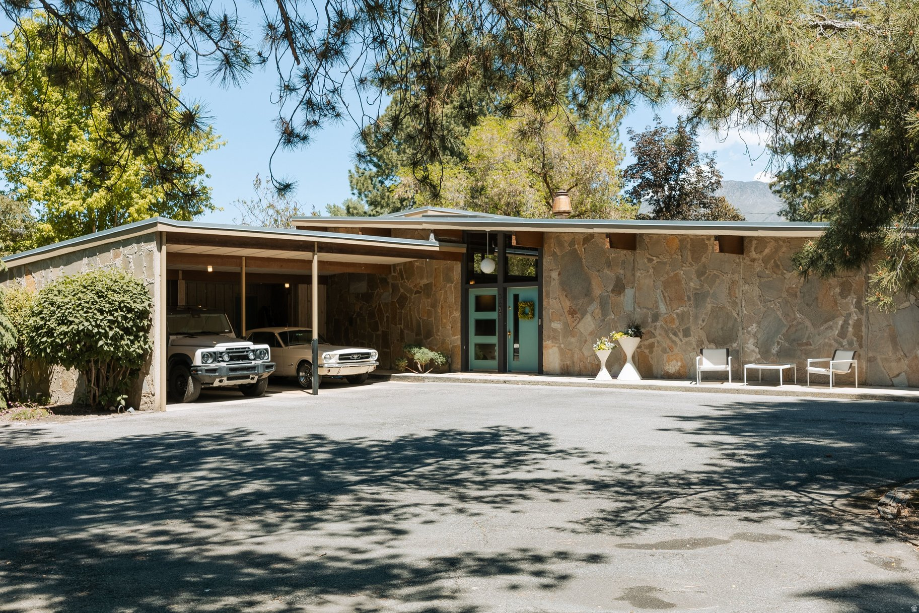 The approach to this home remains one of my favorites, characterized by massive aggregate facades. While this material is a common mid-century detail in commercial buildings, this home utilizes large aggregate wall forms that were cast flat and tilted into place. Stephen MacDonald favored this tilt-up construction for its efficiency and affordability, as well as its alignment with "soft modern" or organic modern design. These walls transition seamlessly from the interior to the outdoors, blurring the lines between the two environments, while post-and-beam construction ties the upper portion together with beautiful wood. The interior features a water feature that runs through the home like a stream, bisecting the main room. Large boulders, polished by years of use as stepping stones, enhance the organic aesthetic. Floor-to-ceiling glass walls at the rear open to a long fountain, ensuring the sound of water echoes throughout the property. The home retains its original mid-century architectural details, including beautifully integrated pegboard and pristine light wood veneer. To complement these features, Anne-Marie Barton has added subtle updates, including the art of Kintsugi adopted by my seller. This Japanese influence reflects Stephen MacDonald's own design history, such as his Millcreek office, which featured shoji screens. This home truly represents a perfect balance of architectural purity and thoughtful modern touches.