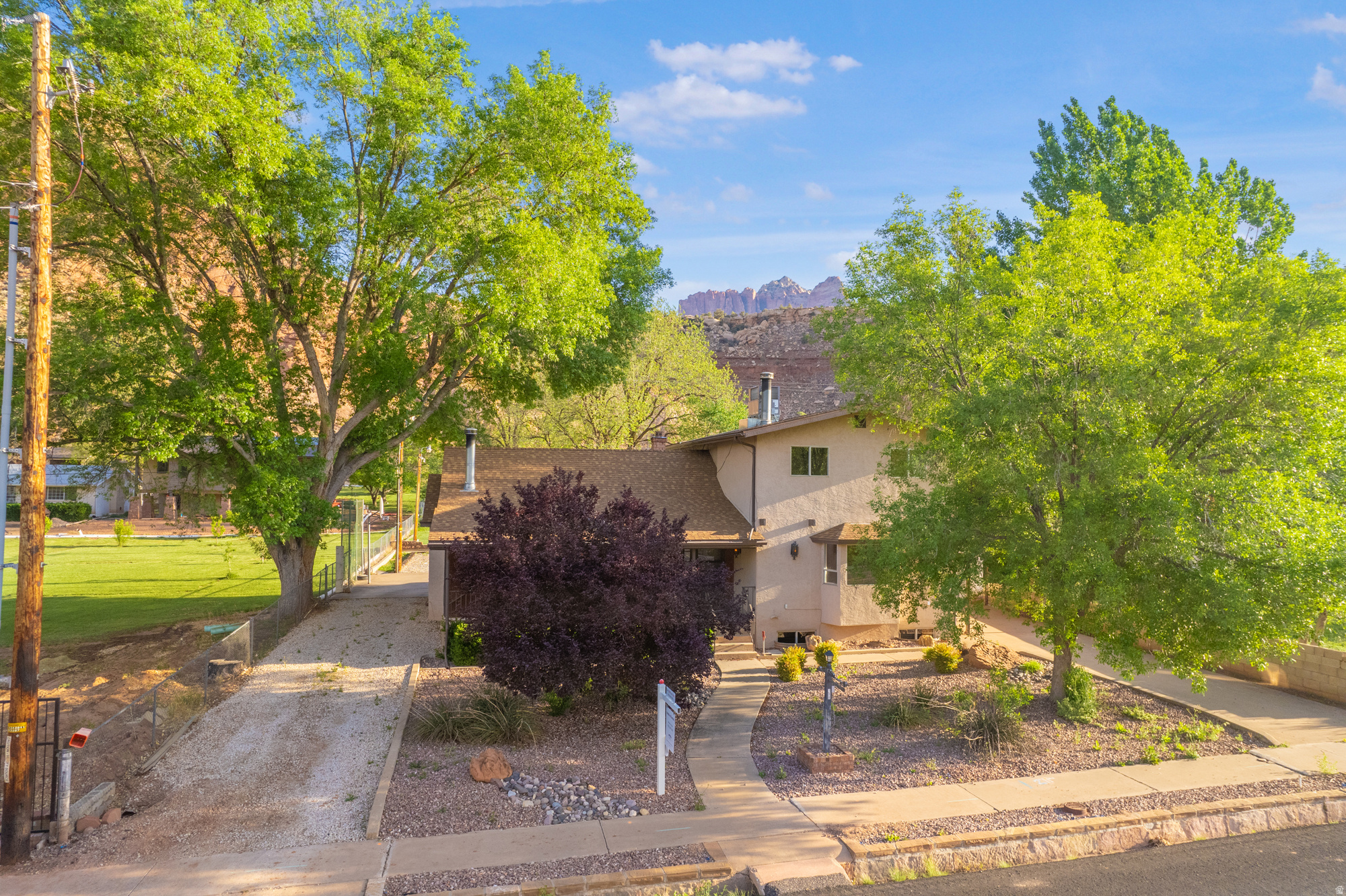 Located on a lush, fully fenced .98-acre lot just minutes from the gates of Zion National Park, this estate offers a rare combination of space and self-sufficiency. The property is a productive homestead, featuring 1.5 shares of Rockville Town Ditch Company irrigation water with a clever hybrid system that utilizes both flood and pressurized lines for the garden and grounds. With horse privileges and a gravel parking area for trailers or equipment, this property is perfectly suited for a classic Southern Utah lifestyle.  The residence is a sturdy, light-filled sanctuary featuring six bedrooms and three-and-a-half bathrooms. While the home retains its original character, the essential infrastructure updates have been completed, including a new roof, new heating and cooling systems, and fresh carpet. The functional layout offers two separate family rooms-each with a wood-burning fireplace-as well as a dedicated office and a creative craft area.  Practicality is found in every corner, from the abundant storage to the large laundry and mudroom that serves as a transition from the outdoors. The grounds are already optimized for small-town living, complete with a chicken coop and run, a storage shed with a workbench, and mature pecan, apple, and pear trees. This is a rare opportunity to secure a high-utility property in Rockville that is move-in ready today, while offering the "good bones" and water security needed to build significant equity as you customize it over time.