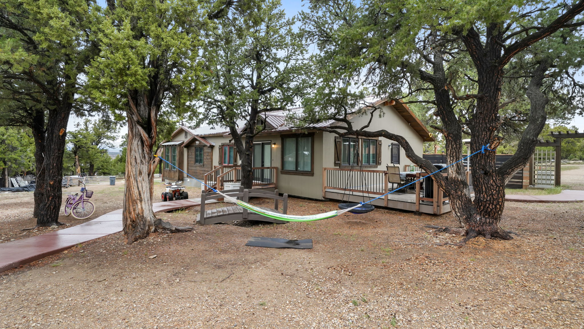Tucked away on 5.48 private acres, this beautifully remodeled rambler offers the perfect blend of rustic charm and upscale comfort. With 1,724 square feet, 4 bedrooms, and thoughtfully crafted living spaces, this one-of-a-kind property feels like a peaceful mountain retreat while still offering modern finishes. Inside, you'll find stunning custom woodwork, vaulted ceilings, and a warm wood-burning stove that creates an inviting cabin feel throughout the home. The 2022 remodel brought updated finishes and thoughtful touches that perfectly balance character and style. Step outside and experience the true magic of the property. Expansive outdoor living spaces are designed for gathering, entertaining, and enjoying nature. A fully built-out fire pit area, outdoor stage with backdrop, circular driveway, and multiple storage sheds make this property as functional as it is unique. The metal roof and private well add durability and self-sufficiency, while the secluded setting offers unmatched peace and privacy away from the hustle and bustle of everyday life.  Whether you're looking for a full-time residence, private retreat, or entertainer's dream property, this rare acreage delivers a lifestyle unlike any other. Note: Follow the red arrow signes for the correct way to get to the property. Maps takes you through private property. Call listing agent for showings!  The proper permits were not purchased for the home and didn't undergo the inspections. Part of this home is not on a permanent foundation and is on railroad ties. This home will not qualify for lending and is cash only. An addendum will need to be signed stating the buyer is aware of the Note of Noncompliance due to the permits and missed inspections.