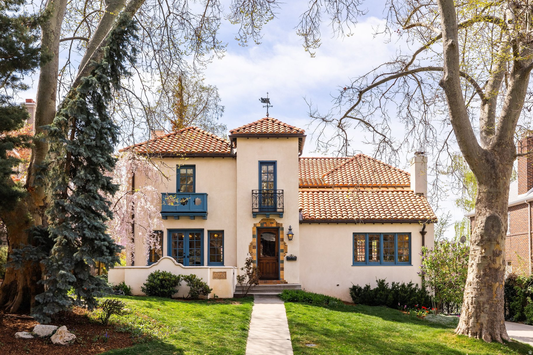 One of Federal Heights' most architecturally significant homes, this Spanish Colonial Revival-originally built in 1928 and known as the Nels G. Hall House-is listed on the National Register of Historic Places and has been carefully restored for modern living. Set on a tree-lined lot, the approach begins with a gated, radiant-heated driveway, framed by a hand-forged Spanish gate dating to the late 1800s-an incredible architectural element that now functions as a fully integrated electric gate, creating a secure, enclosed environment ideal for pets, kids, and everyday peace of mind. Beyond, a series of private outdoor spaces unfold, including a courtyard and layered terraces that create a true sense of arrival. Inside, hand-painted Moorish tiles, vaulted ceilings, and four fireplaces anchor the home's original character, while thoughtful updates-such as limestone surfaces and integrated systems-enhance everyday livability. A comprehensive renovation completed between 20032006 expanded and refined the home while maintaining its architectural integrity. The layout offers both inviting gathering spaces and quiet retreats across multiple levels, including a rare upper-level configuration with four bedrooms and three baths-an increasingly hard-to-find setup in this neighborhood. Equally rare for the area, the property offers garage space for three cars, including a newer detached two-car garage with a climbing wall, along with the original attached garage-heated and ideal for a ski or bike room, workshop, or additional storage. Surrounded by mature trees and set in one of Salt Lake City's most established neighborhoods, the property offers privacy with immediate access to the University, downtown, and nearby foothill trails. A rare opportunity to own a nationally recognized historic residence-already thoughtfully adapted for modern living.