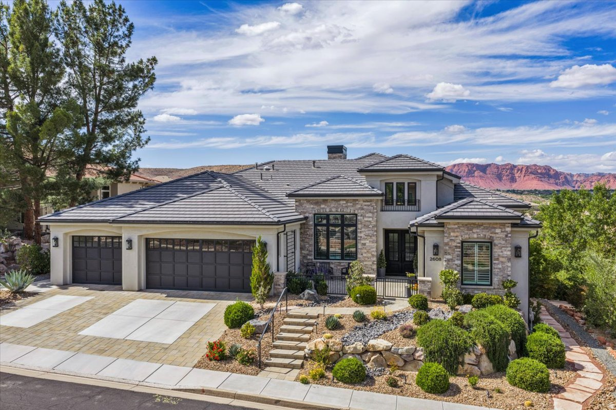 Experience elevated desert living in this stunning 7,700 SF former Parade Home, ideally positioned on the Sunbrook Golf Course with captivating views of the wooden bridge on the signature hole of the golf course and sweeping 180-degree mountain vistas of Red Mountain, Snow Canyon and Pine Mountain.  Thoughtfully designed for both luxury and functionality, this exceptional residence offers 6 bedrooms, 6.5 bathrooms, a private office, and a dedicated art or craft room. The expansive layout includes a children's playroom beneath the garage which, if desired, can be easily converted into a custom home theater or entertainment suite. The downstairs exercise room can also be used as a bedroom, providing the 7th bedroom, if desired. Another downstairs bedroom features custom-built bunk beds, with sleeping space for 7, offering both functionality and charm. The upstairs guest bedroom enjoys private access to the courtyard, making it ideal for use as a casita. The kitchen boasts an exceptional butler's pantry - spacious and elegantly designed, rivaling those found in estate-style residences. Dual laundry rooms - conveniently located on the main level and in the walkout basement - add everyday practicality. The home features soaring 12-foot ceilings, two fireplaces, and abundant natural light throughout. The finishes are truly exquisite - luxurious and refined, elevating every space with exceptional craftsmanship and design.  Outdoor living is equally impressive, with two covered decks and a fire pit designed to take full advantage of the golf course and mountain views, as well as a charming courtyard. Completing the property is a spacious three-car garage and the prestige of owning a former Parade Home in  Sunbrook's most desirable golf course setting. This is a rare opportunity to combine scale, views, and lifestyle in one remarkable residence. Please click on TOUR on top of the listing.
