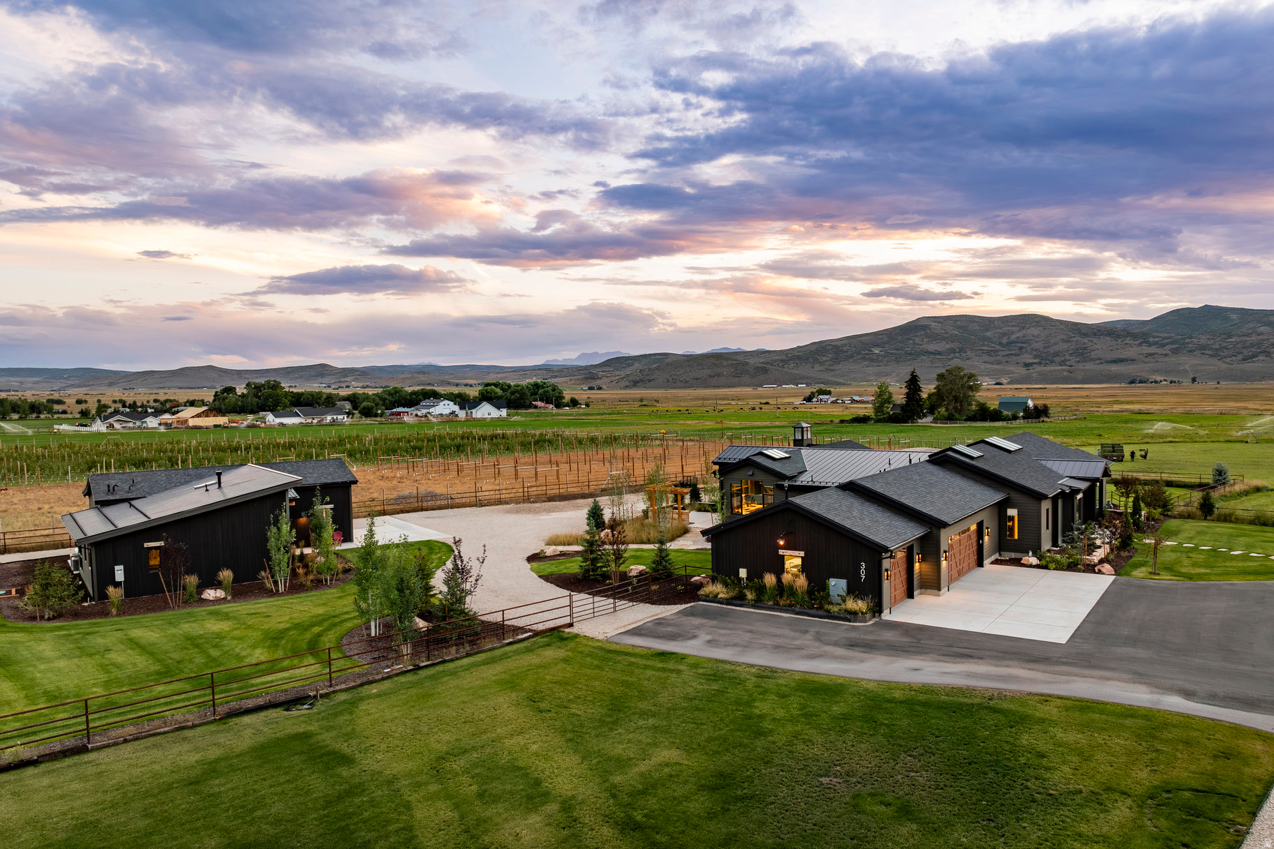 At the end of a peaceful lane in the Kamas valley, on 7.2 acres of ranch land, sits a special property surrounded by protected pastoral grazing lands across the entire valley.Perfectly positioned less than 20 minutes to Deer Valley East Village and just 25 minutes to downtown Park City, you will find a smartly scaled sanctuary-comprising one residential lot and two agricultural parcels-fully fenced and supported by a pressurized irrigation system with ample water shares. The combined 4,929 square feet of living space encompasses a 4,072 sq ft main residence and an 857 sq ft guest house (ADU). A large "Garage-Mahal" (1138 sq ft) adjoins the guest quarters. This single-level modern ranch house aesthetic is defined by artisan craftsmanship, expansive natural light, and a warm blend of wood, steel, and glass. Radiant in-floor heating runs throughout, reinforcing comfort at every turn. The chef's kitchen is anchored by professional-grade, American-made appliances-bringing commercial level utility for family and entertaining. A fully finished 6+ foot lower-level crawl space spans the entire footprint, offering exceptional storage, workspace, or secure safe room/storm shelter. The main residence features two spacious en-suite bedrooms with airy proportions and elevated finishes. The detached ADU extends lifestyle flexibility with its own ensuite bedroom, full kitchen, living area, and a versatile lounge/workspace-ideal for guests, extended living, or creative use. Outdoor living is equally intentional, featuring a timber-frame pergola, natural gas-plumbed grill patio, and a perfectly positioned hot tub terrace overlooking expansive western views across protected open space. Snowmelt-equipped metal roofing, a heated 3-car garage, and dual natural gas generators-serving both structures independently-ensure year-round resilience and uninterrupted comfort. Whole home audio and an extensive camera security system round out the home's features. Furnishings and select farm equipment are negotiable.