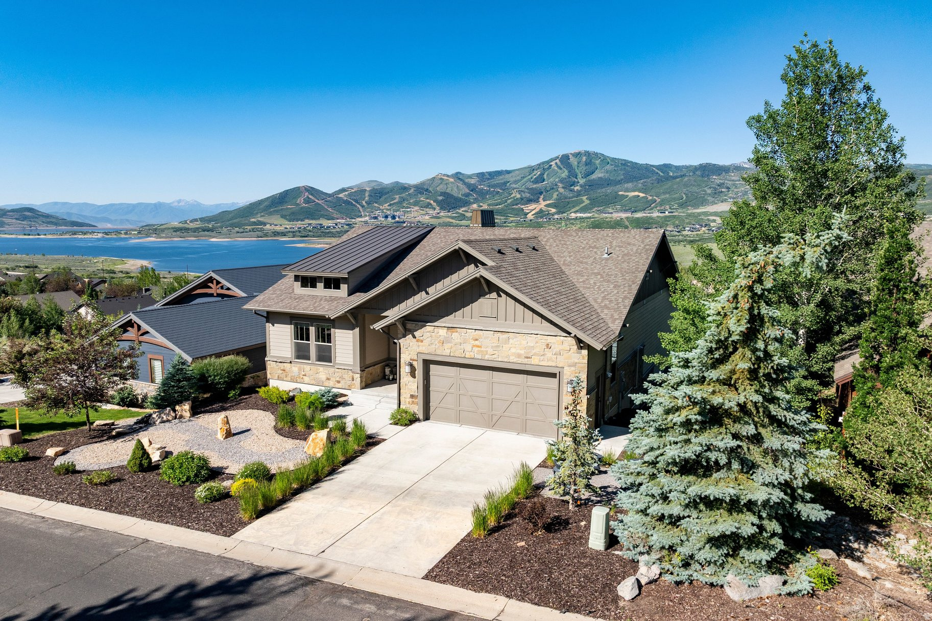 Step through the front door of this stunning mountain contemporary home and the views take center stage. Deer Valley's Bald Mountain and the Jordanelle Reservoir are beautifully framed throughout the main living spaces, creating an immediate sense of arrival and connection to the mountain setting.  Thoughtfully designed for main-level living, the home features an open floor plan with vaulted ceilings, oversized picture windows, and a spectacular great room that flows into the kitchen and dining areas. Designed with entertaining in mind, the open kitchen includes an oversized island, stainless steel appliances, custom alder cabinetry, and a large walk-in pantry.  The main-level primary suite enjoys the same beautiful views and offers a luxurious bathroom with custom cabinetry, granite countertops, a large walk-in shower, separate bathtub, and a spacious walk-in closet. A main-level office and nearby three-quarter bathroom add function and flexibility.  The walkout lower level expands the living space with three large bedrooms, a secondary family room, built-in bar, game area, separate gym, and easy access to the outdoor hot tub. Outdoor spaces include covered living areas, a custom water feature, flagstone patio, and a xeriscaped 0.25-acre lot. A short, flat driveway adds ease in every season.  Located in Deer Mountain, approximately ten minutes from Park City and just minutes from Deer Valley's East Village and the marina at Jordanelle Reservoir, this home offers the rare combination of panoramic views, thoughtful design, and effortless mountain living.