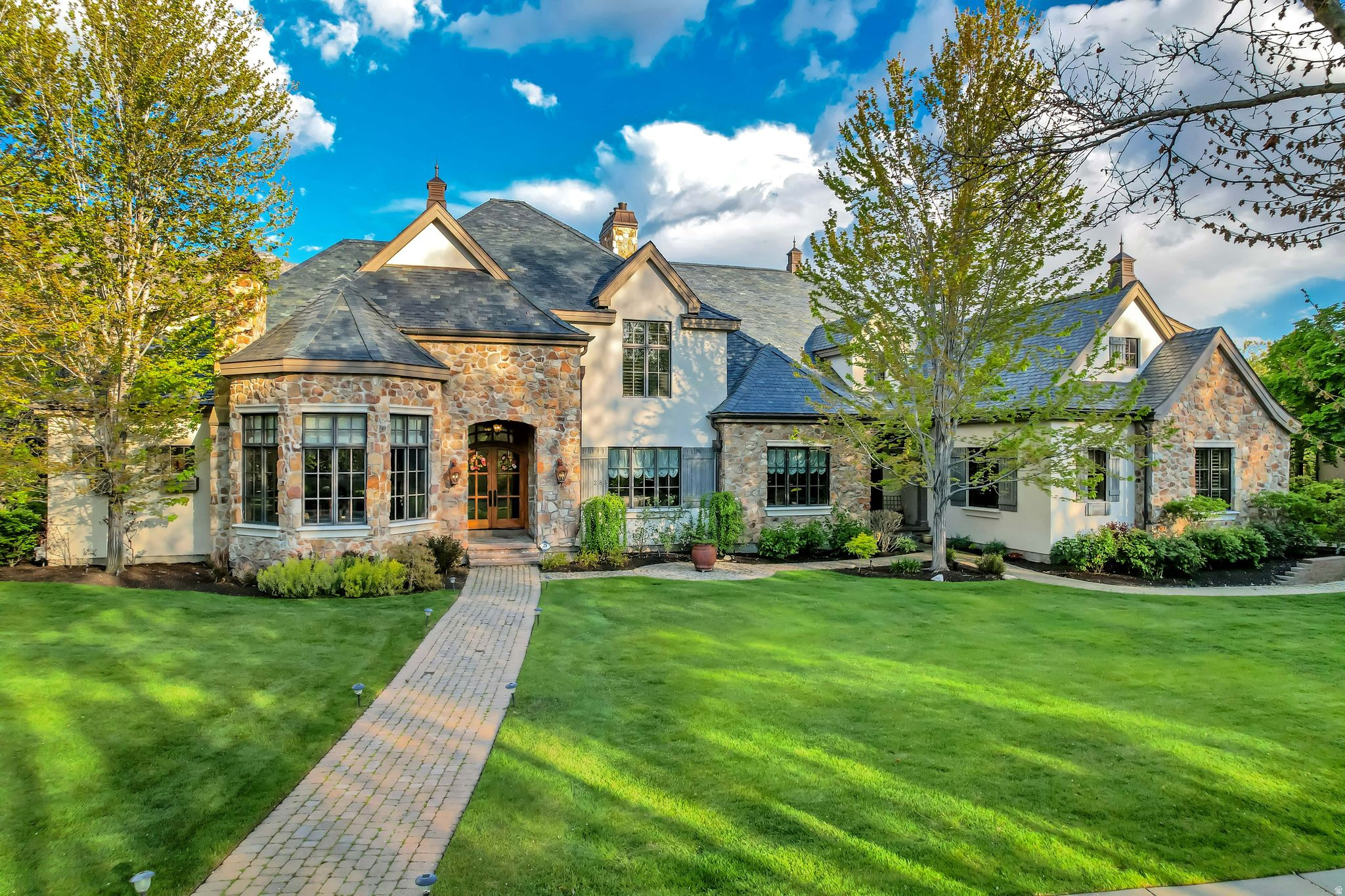 Timeless estate in the highly coveted Stone Gate community of Provo, blending classic architectural charm with luxury amenities and beautifully designed gathering spaces throughout. Thoughtfully crafted with soaring vaulted ceilings, expansive windows, dual staircases, and beautiful French doors, this warm and inviting residence was designed for both refined living and effortless entertaining. The interior features high-end Wolf appliances, HVAC system, two laundry rooms conveniently located on both the main level and upstairs, an elevator providing accessibility to every floor, and generous storage throughout. Spacious living areas flow seamlessly across the home, including a dedicated theater room, private gym, basement kitchen, indoor sports court, and oversized 4-car garage. Step outside to beautifully designed patio spaces off both the main level and basement, where peaceful waterfall features and stunning views of Mount Timpanogos create an incredible backdrop for year-round enjoyment. Located near the Provo River Bottoms, residents enjoy direct access to the Provo River and scenic river walk trails, along with Stone Gate's sought-after amenities including the beach-style pool, pickleball courts, basketball and volleyball courts, and more. Combining timeless design, exceptional functionality, and one of Provo's most desirable locations, this remarkable estate offers a rare opportunity to experience luxury living in one of Utah County's premier communities. Buyer/Buyer's Agent to verify all information.