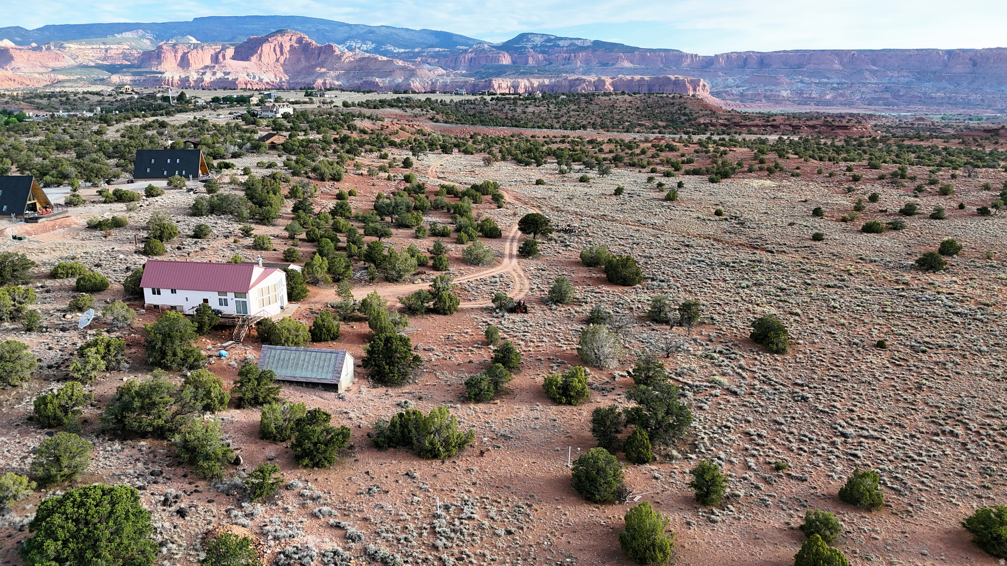 Located on a private 40-acre parcel adjacent to the Fremont Gorge Wilderness Study Area, this southern Utah property combines privacy, scenic surroundings, and convenient access to some of the state's most recognizable public lands. Accessed via approximately one-third of a mile of private lane, the property is situated just over two miles from Capitol Reef National Park. It offers expansive views across the surrounding red-rock landscape. The custom-built 3+ bedroom 3-bathroom cabin encompasses approximately 2,625 square feet and features a multi-level design that complements the natural terrain. Vaulted ceilings in the kitchen and great room create an open living area, while large windows frame views of the nearby cliffs, mesas, and surrounding pinyon-juniper hillsides. The cabin includes large bedrooms, two full bathrooms, walk-in closets, and generous storage throughout. Additionally, the cabin is connected to both Torrey City water and community electricity. A wraparound deck extends the living space outdoors and provides multiple locations to enjoy the surrounding scenery throughout the day. Artistic details throughout the cabin, including custom fireplace features and preserved period design elements, reflect the home's original character. While much of the interior maintains its classic style, several recent improvements have already been completed, including a new roof and updated kitchen flooring. Adjacent to the cabin is a detached two-car garage with additional workshop space suitable for equipment storage, projects, or recreational gear. A short walk from the home leads to a greenhouse containing a 30-foot swim lane, creating a unique feature that can be enjoyed in a protected environment. The land itself offers a diverse mix of terrain. A large, level open area provides usable ground around the improvements, while the remainder of the acreage transitions into scenic red rock ridges covered with mature juniper, pinyon pine, and scattered sage. Portions of the property are fenced, and the natural landscape offers privacy while preserving the area's native vegetation. The surrounding location provides direct access to an exceptional variety of outdoor recreation. The Fremont Gorge Wilderness Study Area borders the property, while Capitol Reef National Park is located just over two miles away. Nearby destinations include the Fremont River, Cathedral Valley, Fish Creek Cove, The Any Hill, and numerous hiking opportunities throughout the region. Hundreds of miles of established ATV and UTV routes can also be accessed nearby, allowing exploration of the surrounding public lands. Utah Scenic Byway 12 lies nearby and provides convenient access to additional recreation throughout southern Utah. Traveling south leads toward Dixie National Forest before continuing to Bryce Canyon National Park, while Fishlake National Forest is located to the north, offering additional opportunities for hiking, camping, fishing, horseback riding, and seasonal recreation. The property's rural location also provides favorable conditions for observing the night sky. With a reported Bortle Class 2 rating and approximately 21.96 sky magnitude, the area experiences minimal light pollution, allowing for exceptional visibility of stars and celestial features on clear evenings. Whether used as a private recreational retreat, seasonal residence, or base camp for exploring south-central Utah, this property offers a combination of acreage, comfortable improvements, and proximity to an extensive network of public lands and outdoor destinations. The blend of established improvements, natural terrain, and nearby recreational access creates a unique opportunity within one of Utah's most scenic regions.