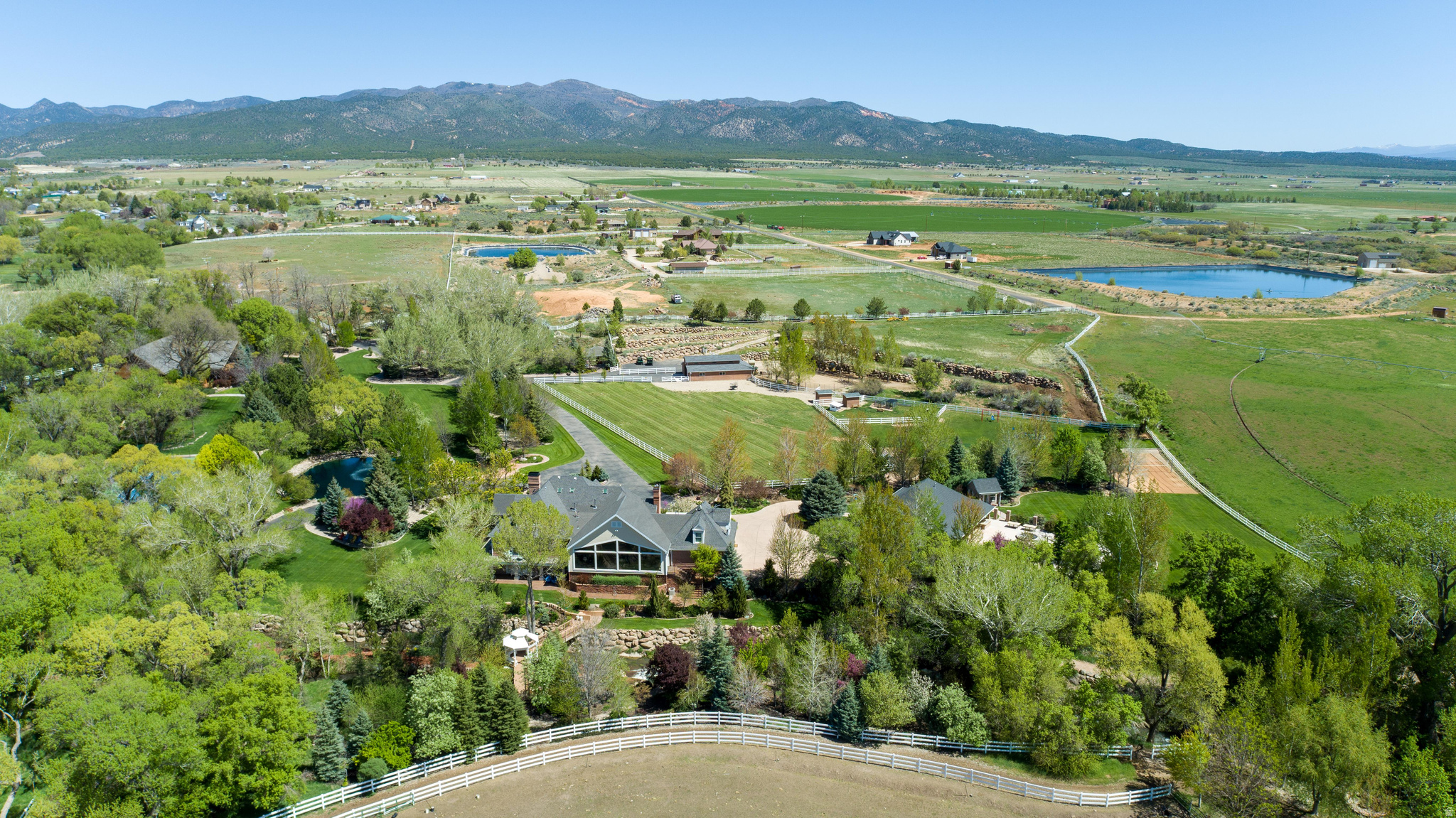 Private 13+ Acre Mountain Luxury Home in New Harmony | Pool & Pool House | Tennis/Pickleball Court | Pond | Pasture & Barn | Playground | Volleyball Court | Water Rights | Zion Kolob & Pine Valley Mountain Views | Ash Creek runs through it!  Welcome to one of Southern Utah's most extraordinary private estates, located in the peaceful mountain community of New Harmony at the base of the Pine Valley Mountains. Set on 11+ beautifully landscaped acres, this remarkable property offers over 7,500 square feet of living space, combining refined luxury with the serenity of a rural retreat. From the moment you enter the circular drive and gated entrance, the estate unfolds with manicured grounds, mature landscaping, and the gentle sound of Ash Creek running through property. The residence features five bedrooms, six bathrooms, and multiple gathering spaces including formal living and dining areas, fireplaces, and a spacious main-level primary suite. Expansive windows frame views of the surrounding valley and the dramatic Kolob Mountains of Zion National Park. The chef's kitchen is equipped with Wolf and Sub-Zero appliances, a Scotsman pebble ice maker, generous pantry and food storage areas, and a full laundry room with double washer/dryer capacity. Designed for both entertaining and everyday enjoyment, the property offers exceptional indoor-outdoor living with multiple decks and patios overlooking the grounds. Beyond the main residence, the estate includes a resort-style pool and fully equipped pool house featuring a gym, sauna, massage room, kitchen, and laundry. Outdoor amenities continue with a tennis/pickleball court, outdoor kitchen, barn, pasture, garden areas, and a picturesque pond with fountain. The property also includes a private well with valuable underground water rights, animal rights for horses or livestock, and extensive fenced and irrigated landscaping. With sweeping mountain views, privacy, and a rare combination of luxury amenities and usable acreage, this estate offers an exceptional opportunity for those seeking a primary residence, private retreat, or legacy property in Southern Utah. Furnishings included with the sale are those present at the property at the time of showing. Listing photos may not accurately reflect current furnishings.