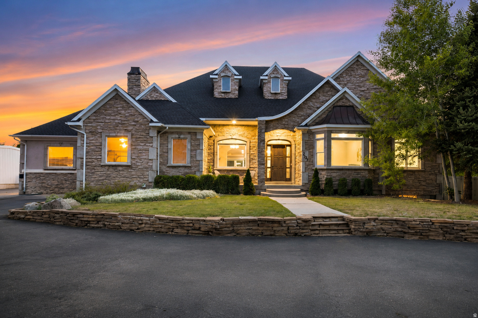 Ask about updates just done to the house: carpet, paint, lighting, deck. From the moment you turn down the private, tree-lined approach, this expansive stone-facade estate commands attention, admiration, and awe. This home invites you to picture your life there. Set on a spacious .64-acre lot in South Jordan, this 5-bedroom, 4.5-bath home offers 6,634 sq. ft. of living space, a 4-car garage, and additional exterior parking. From the warm stone exterior and mature landscaping to the welcoming front entry and beautiful evening curb appeal, the home immediately feels substantial, private, and special. Inside, the floor plan is designed for both everyday comfort and memorable gatherings. The main living areas feel bright and open, with large windows, high ceilings, detailed trim work, recessed lighting, and an easy flow between the kitchen, dining, and living spaces. The kitchen is a natural gathering place with white cabinetry, stainless steel appliances, quartz-style countertops, pendant lighting, a large island with bar seating, and a layout that keeps everyone connected. The home offers spaces for every season of life: quiet mornings in the dining room, relaxed evenings in the great room, movie nights in the theater room, game days in the finished basement, and summer nights outside under the covered patio. The primary suite provides a peaceful retreat with generous space, a tray ceiling, large windows, dual vanities, a soaking tub, separate shower, and excellent closet space. The fully finished basement adds exceptional flexibility with 3 bedrooms, 2 bathrooms, a large recreation/game area, theater room, and kitchenette-style space. It is ideal for entertaining, guests, extended living, or potential rental flexibility, subject to buyer verification and local requirements. Outdoors, the covered patio/deck areas, ceiling fans, mature trees, lawn space, and private-feeling backyard create the kind of setting buyers hope to find but rarely do. With its rare combination of scale, parking, finished basement space, indoor entertainment areas, outdoor living, and South Jordan location, this property is more than a home, it is a place to gather, grow, host, relax, and make memories. Set up an appointment now to see this beautiful home before you make any final decisions on a home, Buyers to verify all the information provided in this listing.
