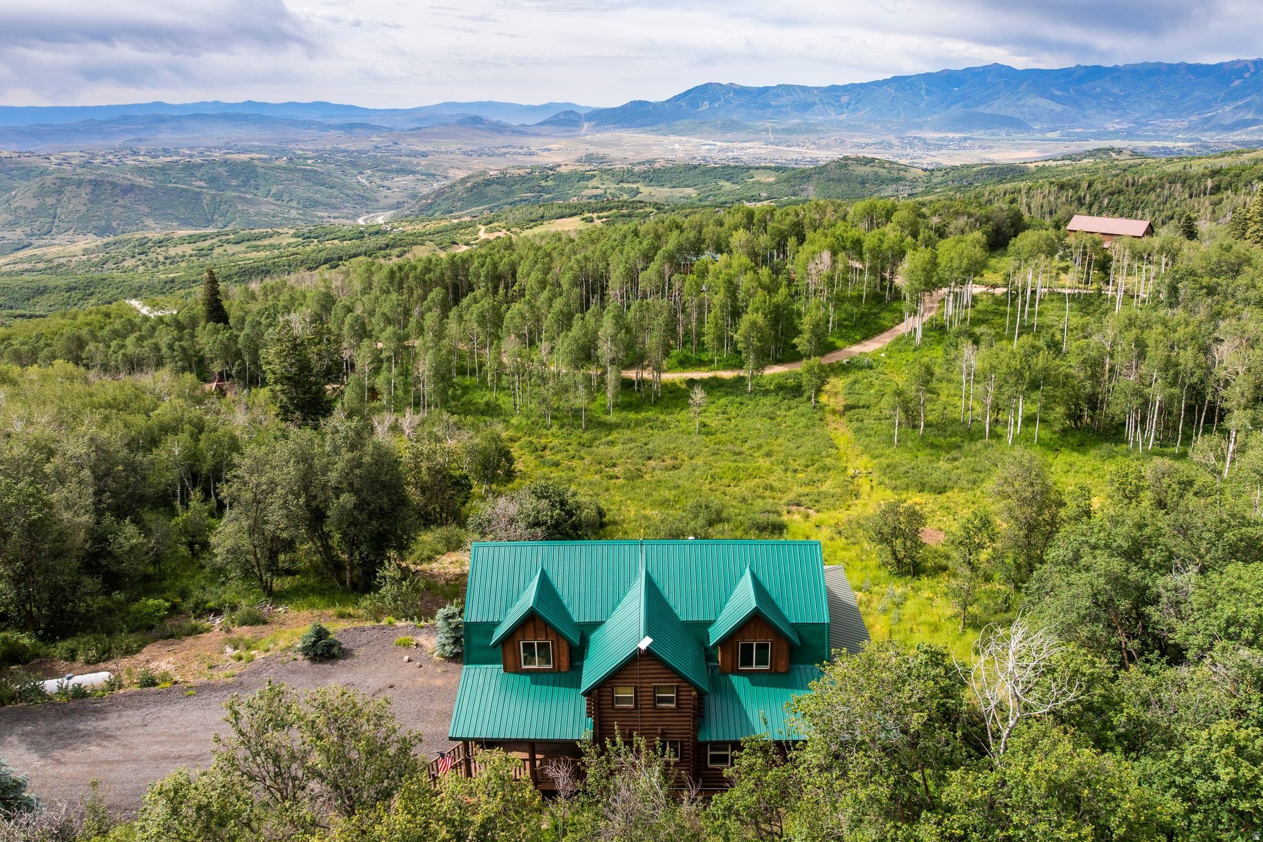 Escape to the serenity of mountain living in this beautiful cabin perched on 1.1 acres in the idyllic community of Tollgate Canyon, located on the border of Park City. Offering over 3,000 square feet, this home combines rustic charm with thoughtful modern updates, including fresh interior paint, new wood flooring, and new kitchen countertops. The natural insulating properties of log construction help promote year-round energy efficiency and comfortable interior temperatures.  Designed for both comfort and functionality, the home features a spacious mudroom/laundry room complete with a convenient dog wash station, a built-in 2-car garage, and flexible living spaces throughout. The walkout lower level offers multiple private entrances and endless possibilities--use it as a fourth bedroom, family room, guest suite, home office, or explore the potential for a future lockout apartment.  Step outside to multiple wrap around decks where you'll enjoy stunning mountain views and peaceful surroundings, creating the perfect setting for morning coffee, evening sunsets, or enjoying the fresh alpine air.  Located in the high-altitude mountain community of Tollgate Canyon, residents enjoy abundant open space, and frequent wildlife sightings, all while being just minutes from I-80 for exceptional year-round access. Conveniently situated only 20 minutes to Kimball Junction's shopping and dining, 30 minutes to world-class Park City skiing, 35 minutes to Salt Lake City, and just 45 minutes via all-highway, no-stoplight driving to Salt Lake City International Airport, this property offers the perfect balance of mountain serenity and everyday convenience.  *Adjacent 3 acre parcel also available for sale.
